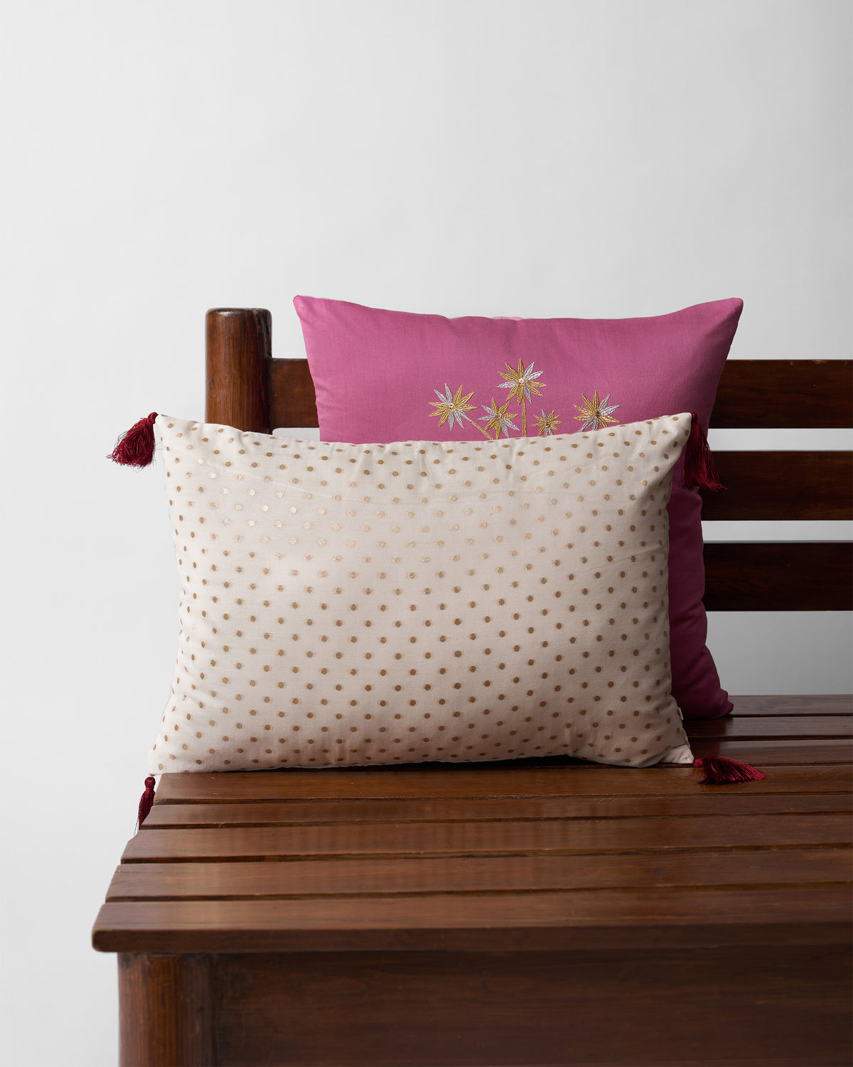 Dottie Cushion Cover in cream with gold dots and maroon tassels.