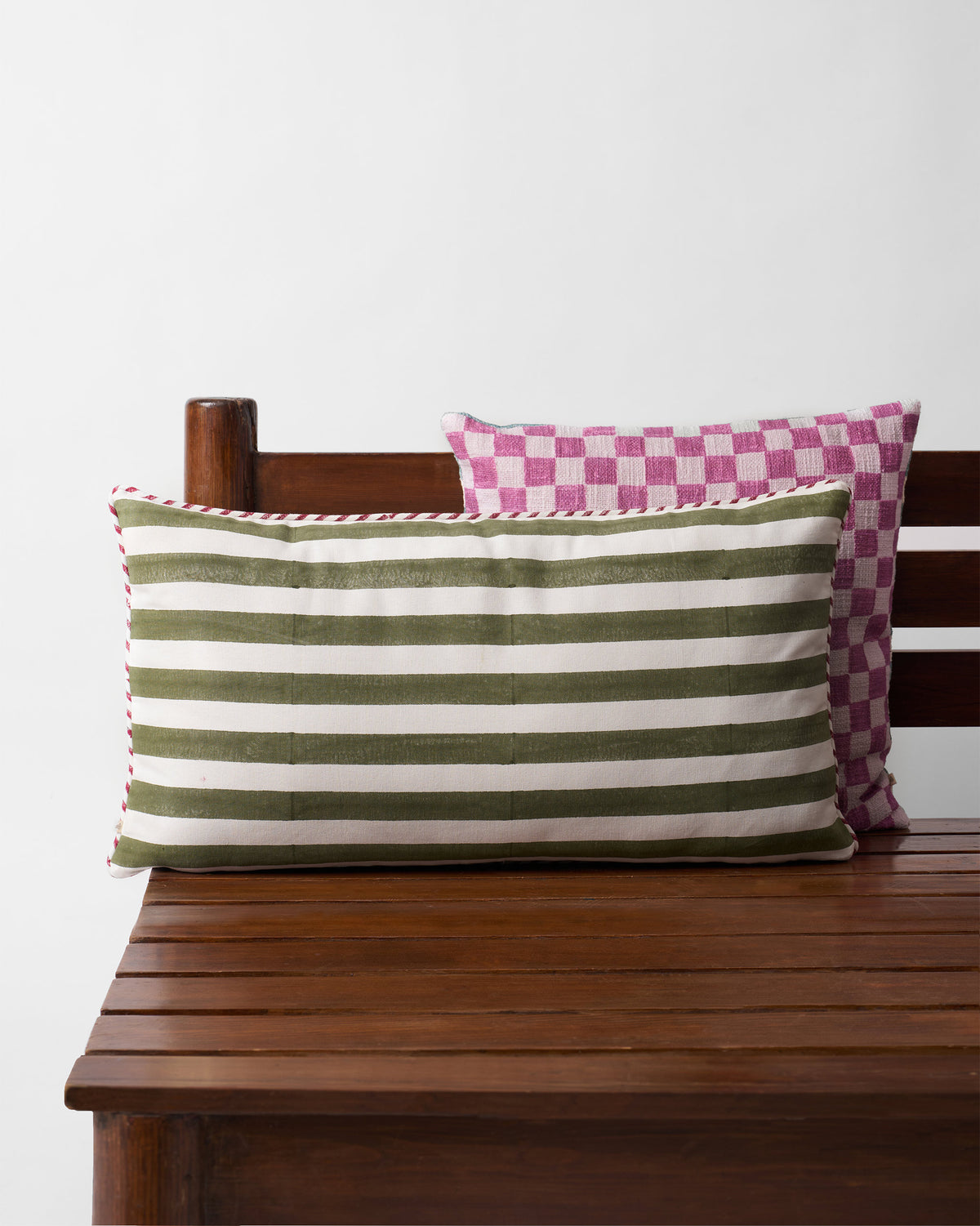 Green and cream striped cushion with a red and cream piped edge.