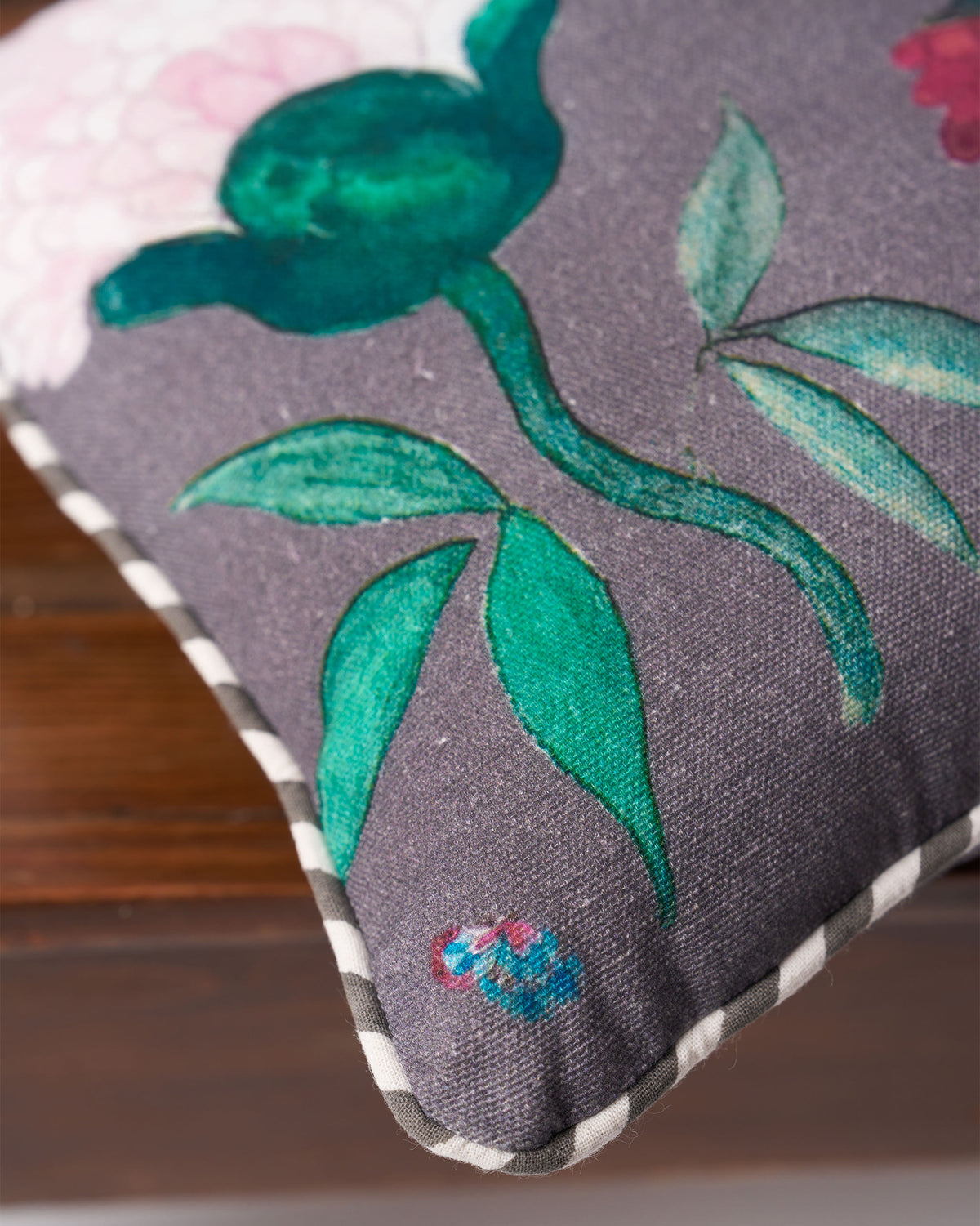 Close-up of green leaves and striped piping on the charcoal Peony car cushion.