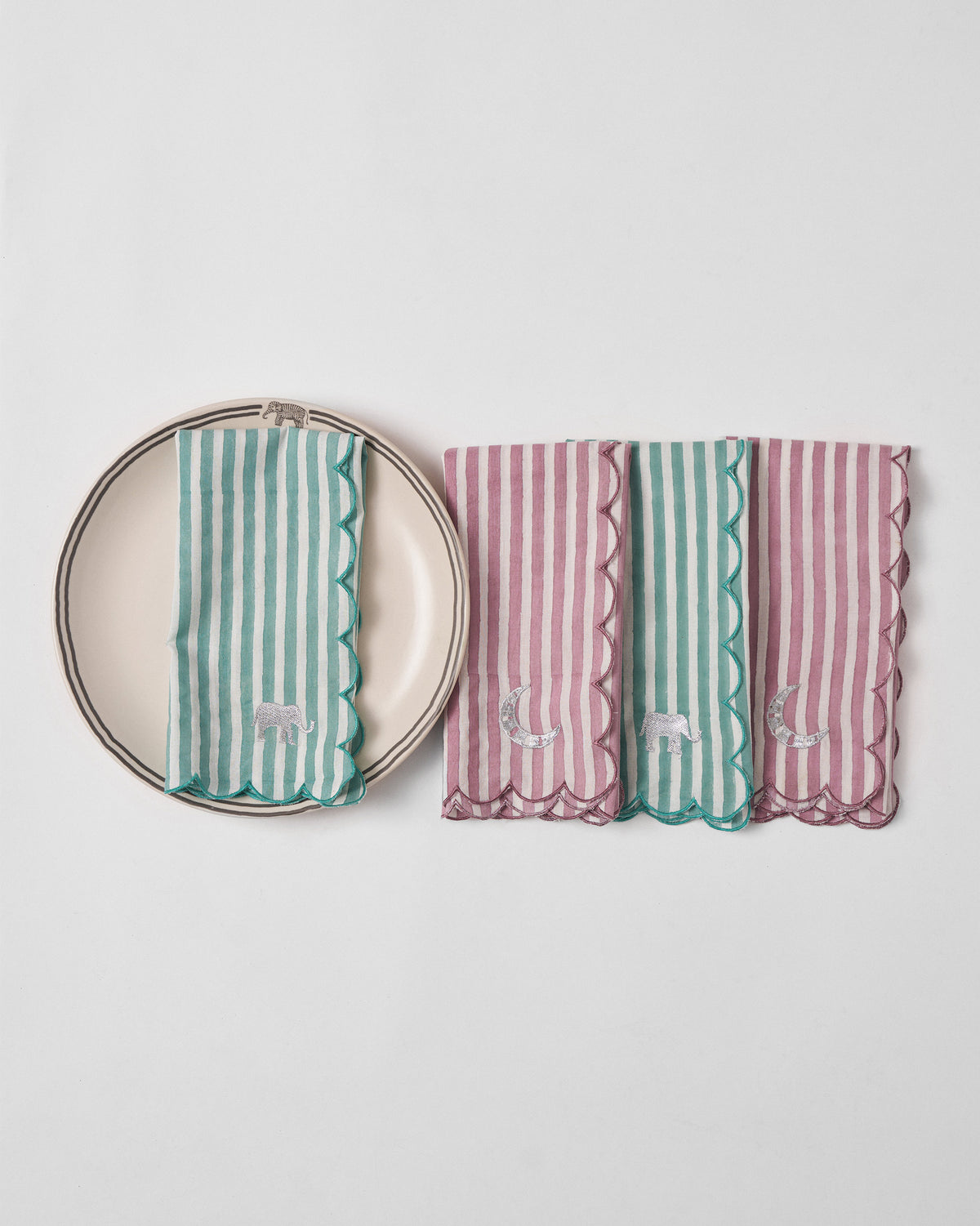 Folded Yamuna napkins with scalloped edges beside a cream plate.