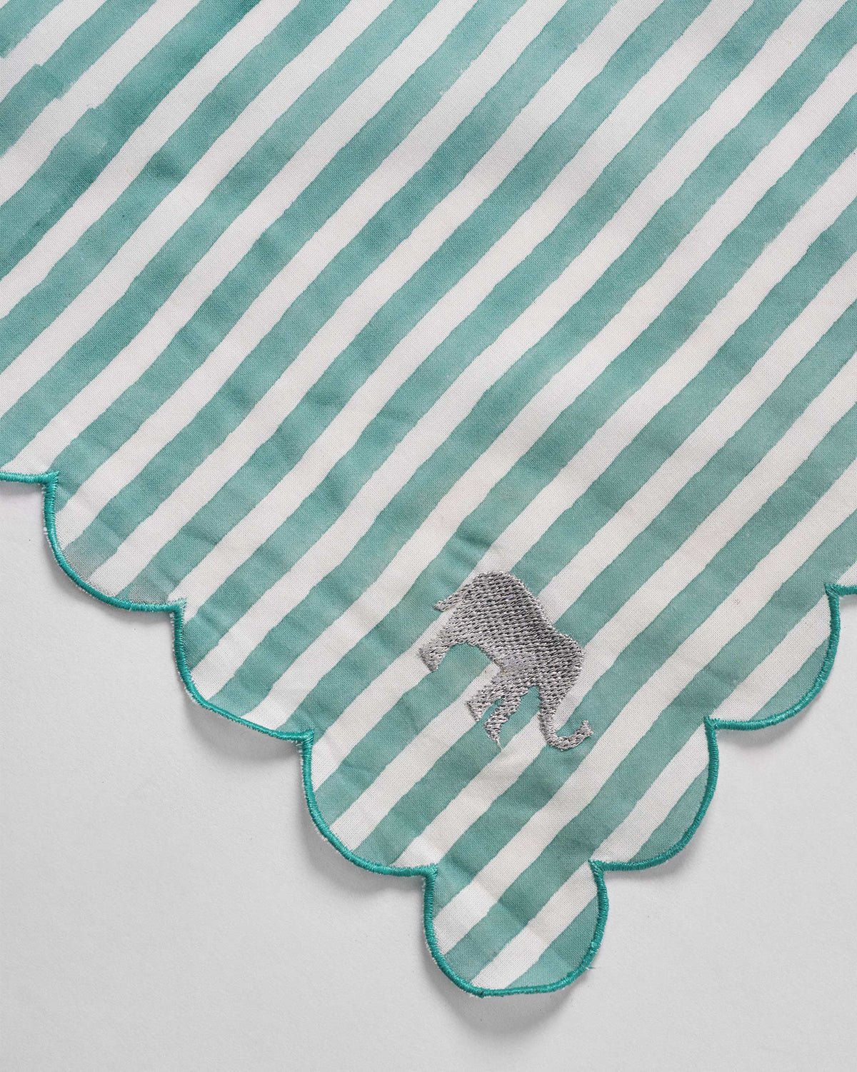 Close-up of a teal striped Yamuna napkin with an embroidered elephant.