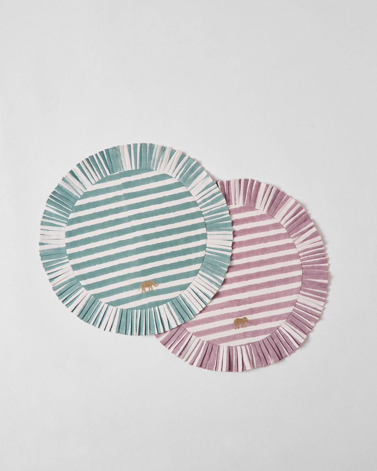 Overlapping teal and mauve Yamuna placemats with fringed borders.