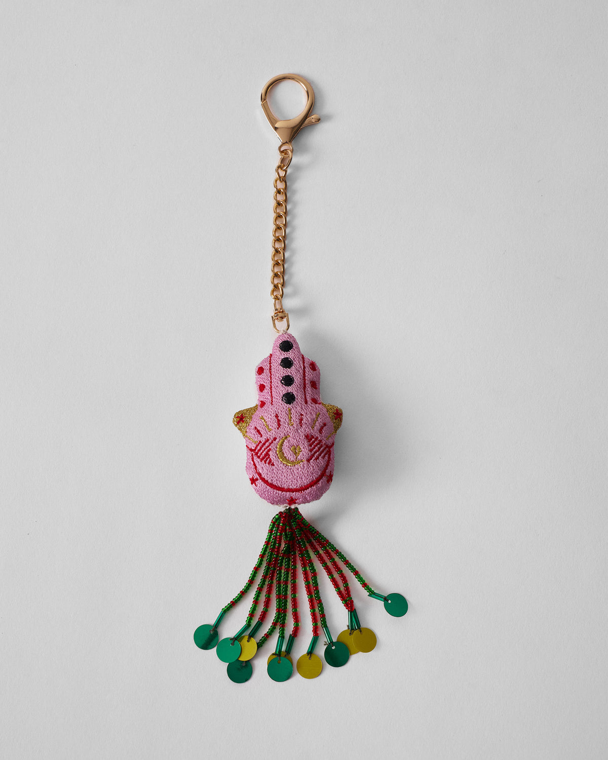 Hamsa Charm in pink hanging full length on a gold chain with beaded tassel.