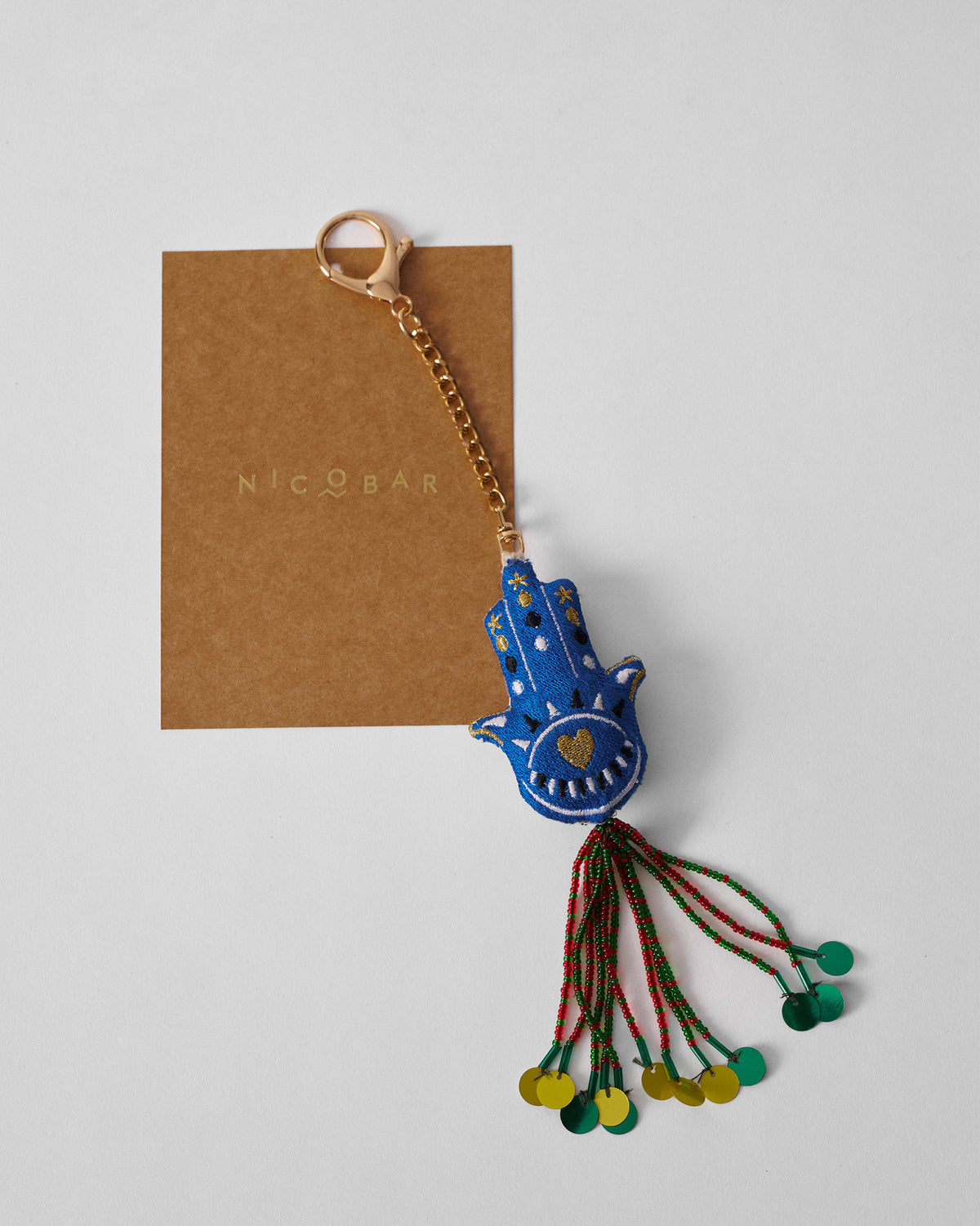 Hamsa Charm in blue with a gold embroidered heart and beaded tassel.