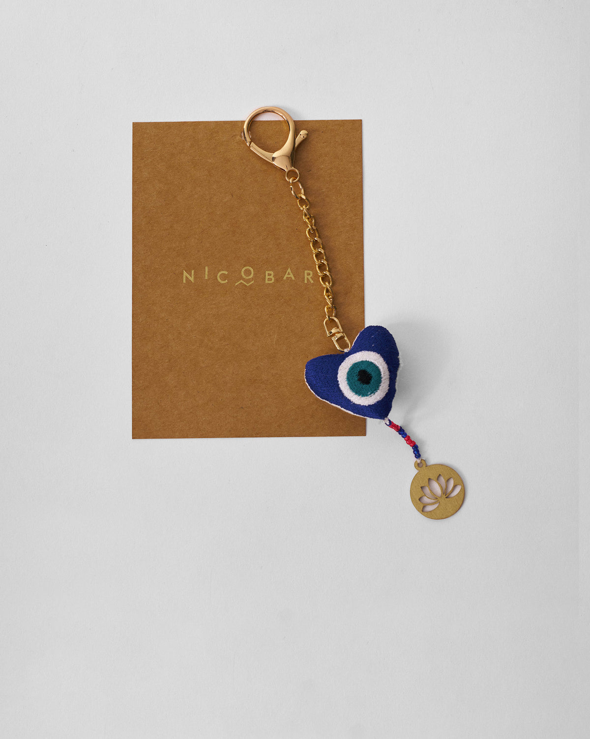 Kamal Charm with a blue heart-shaped eye motif and gold lotus tag.
