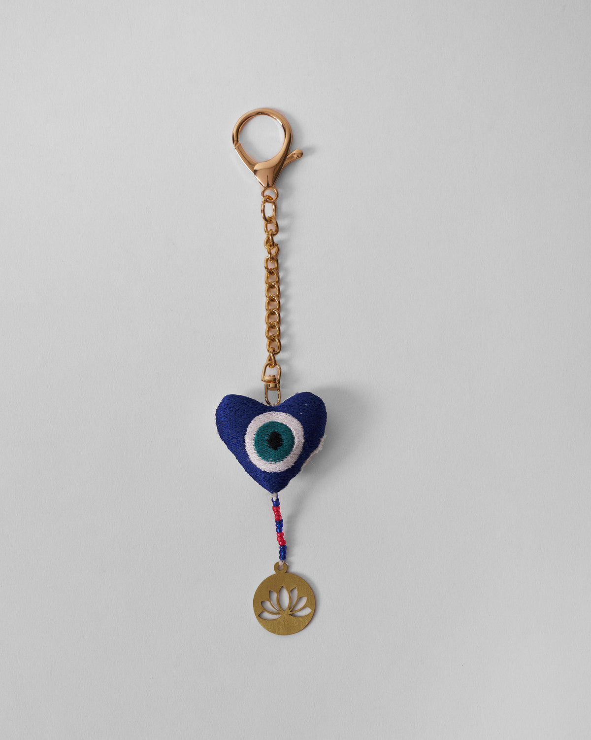 Kamal Charm in blue hanging full length on a gold chain with a lotus tag.
