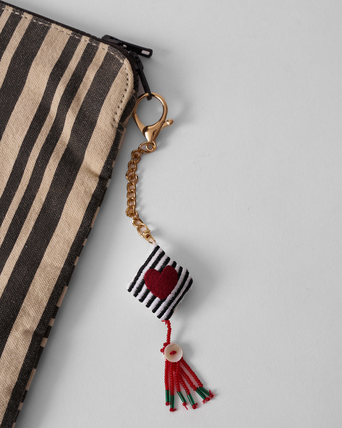 Dil charm with a red heart hanging beside a striped pouch.