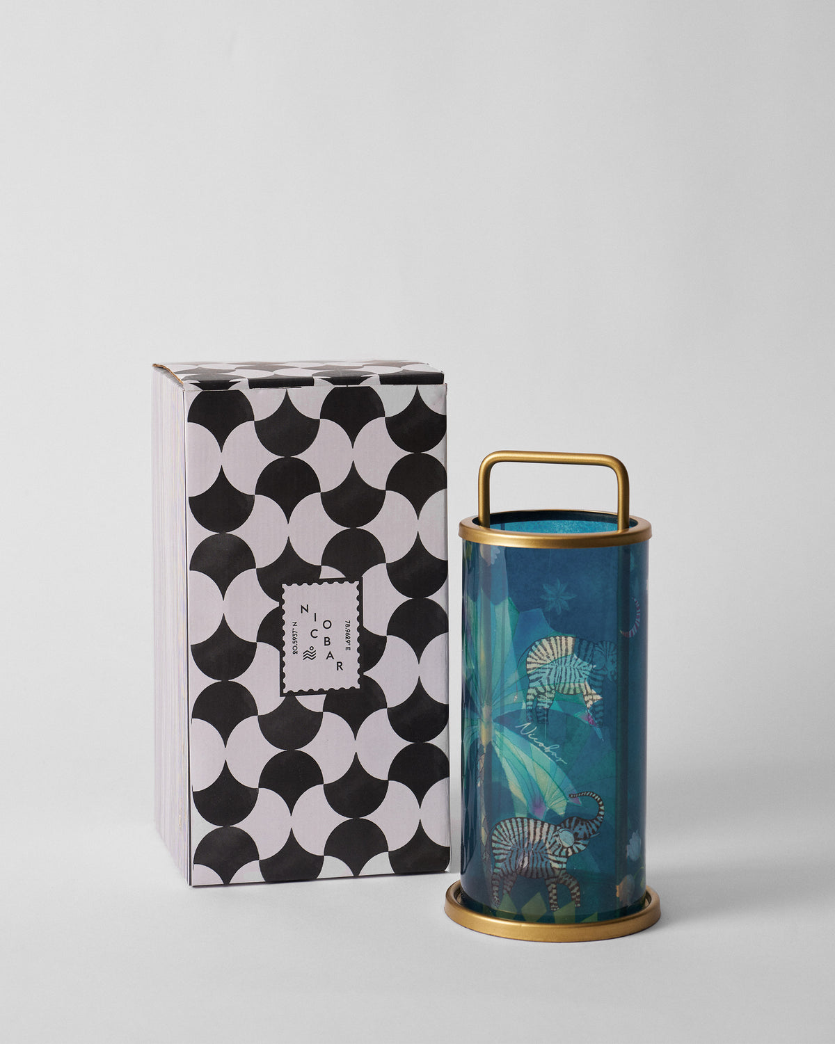 Palm Bloom lantern standing beside its black-and-white patterned Nicobar box.
