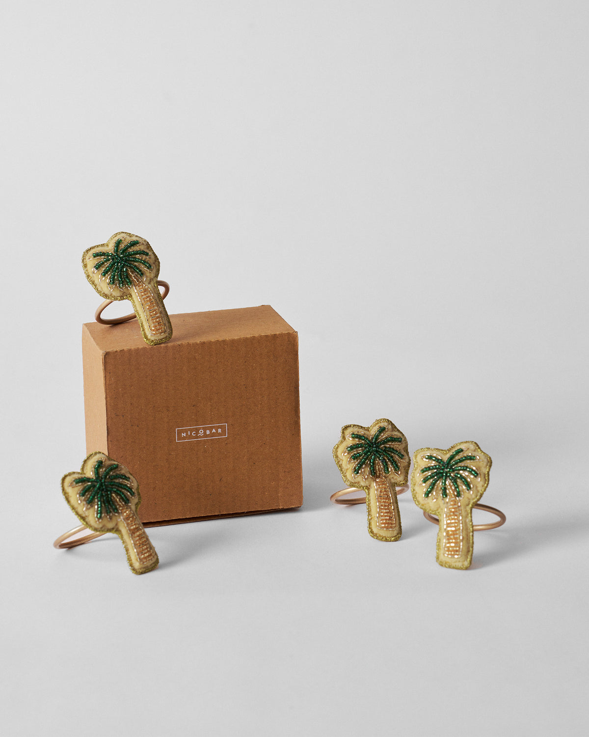 Palm napkin rings arranged around a kraft Nicobar gift box.