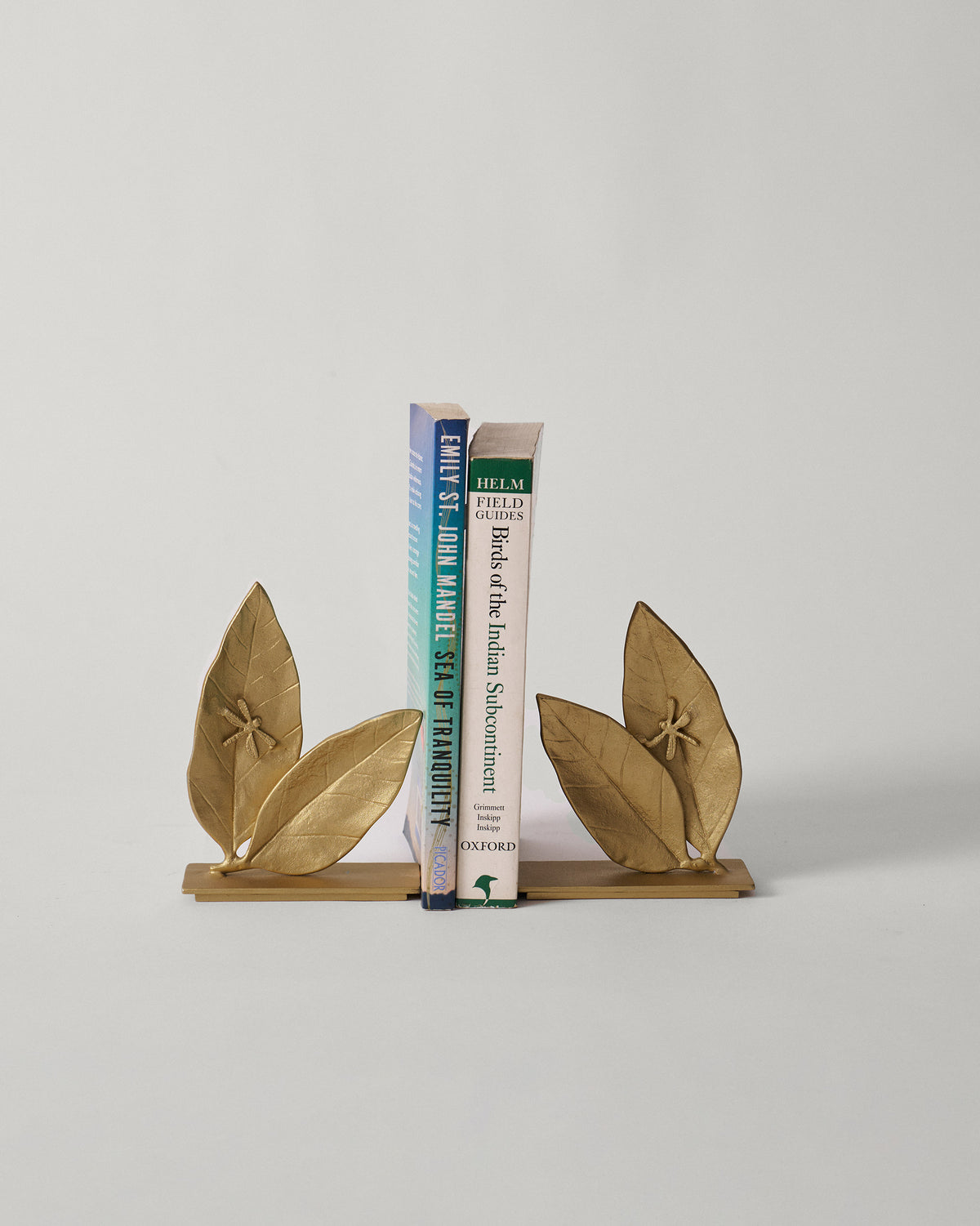 Gold Mogra bookends holding upright books.