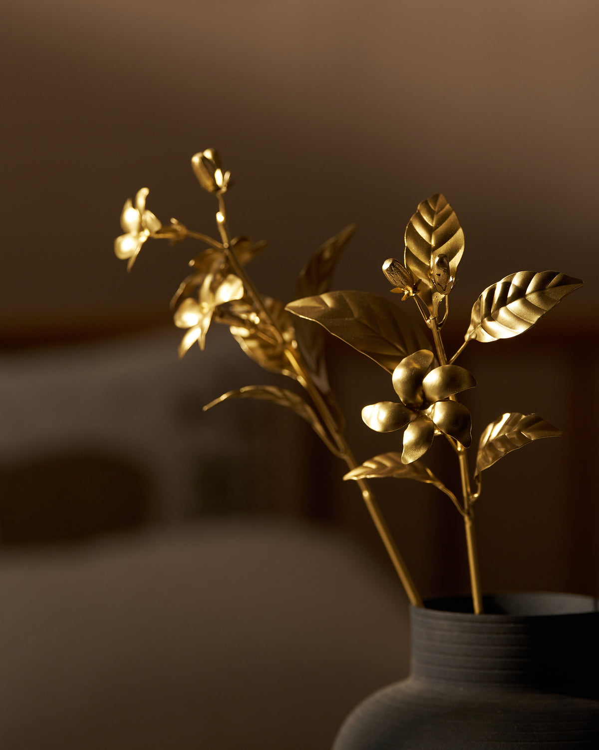 Gold Mogra floral stems rising from a dark vase.