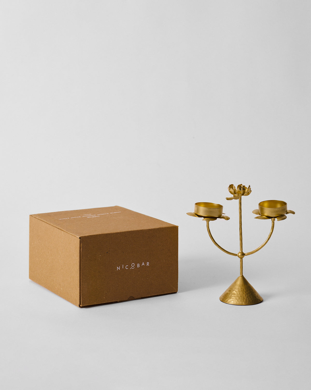 Gold Mogra bud tealight beside a brown Nicobar box.