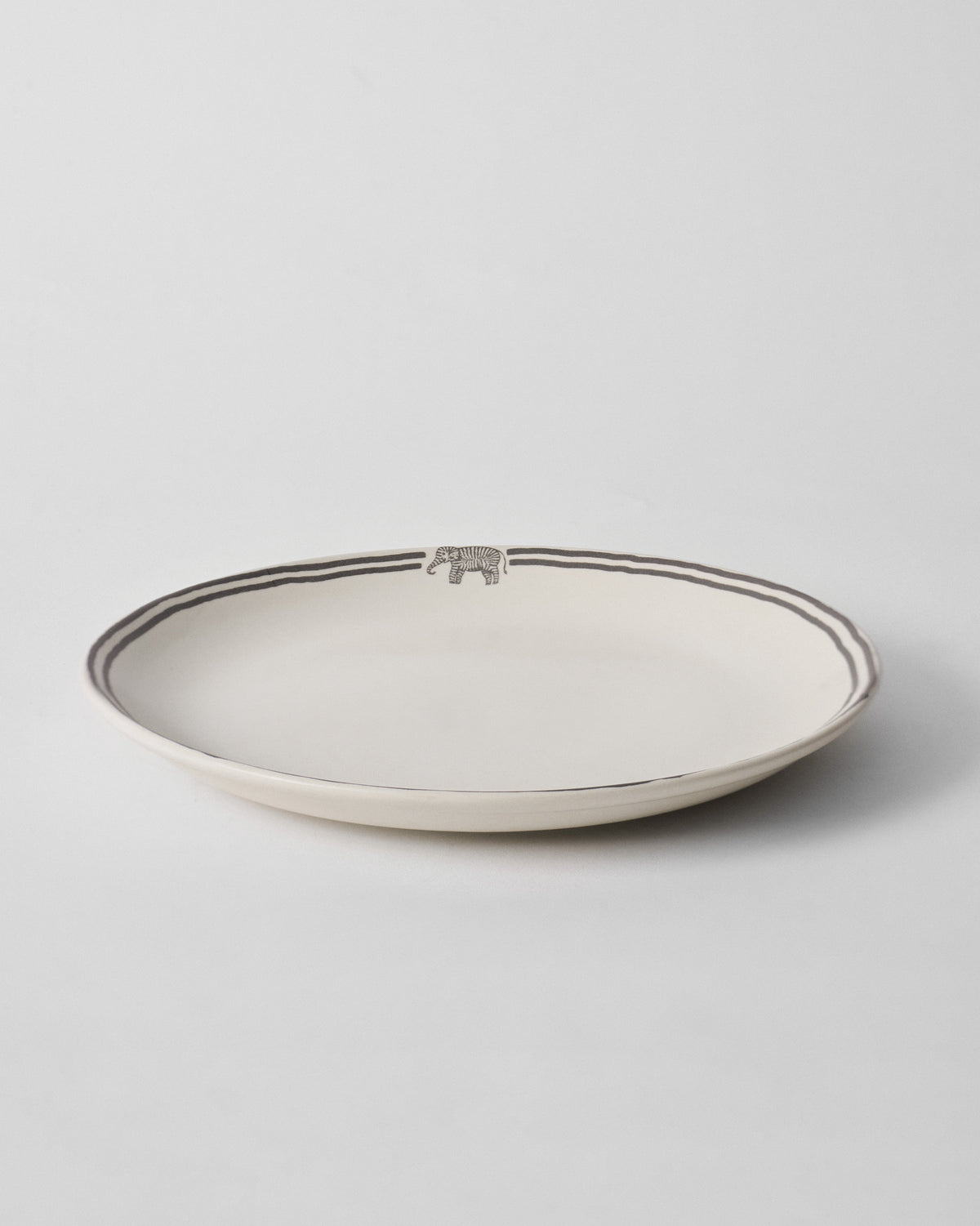 Side view of a Tusk Dinner Plate with a small elephant motif on the rim.