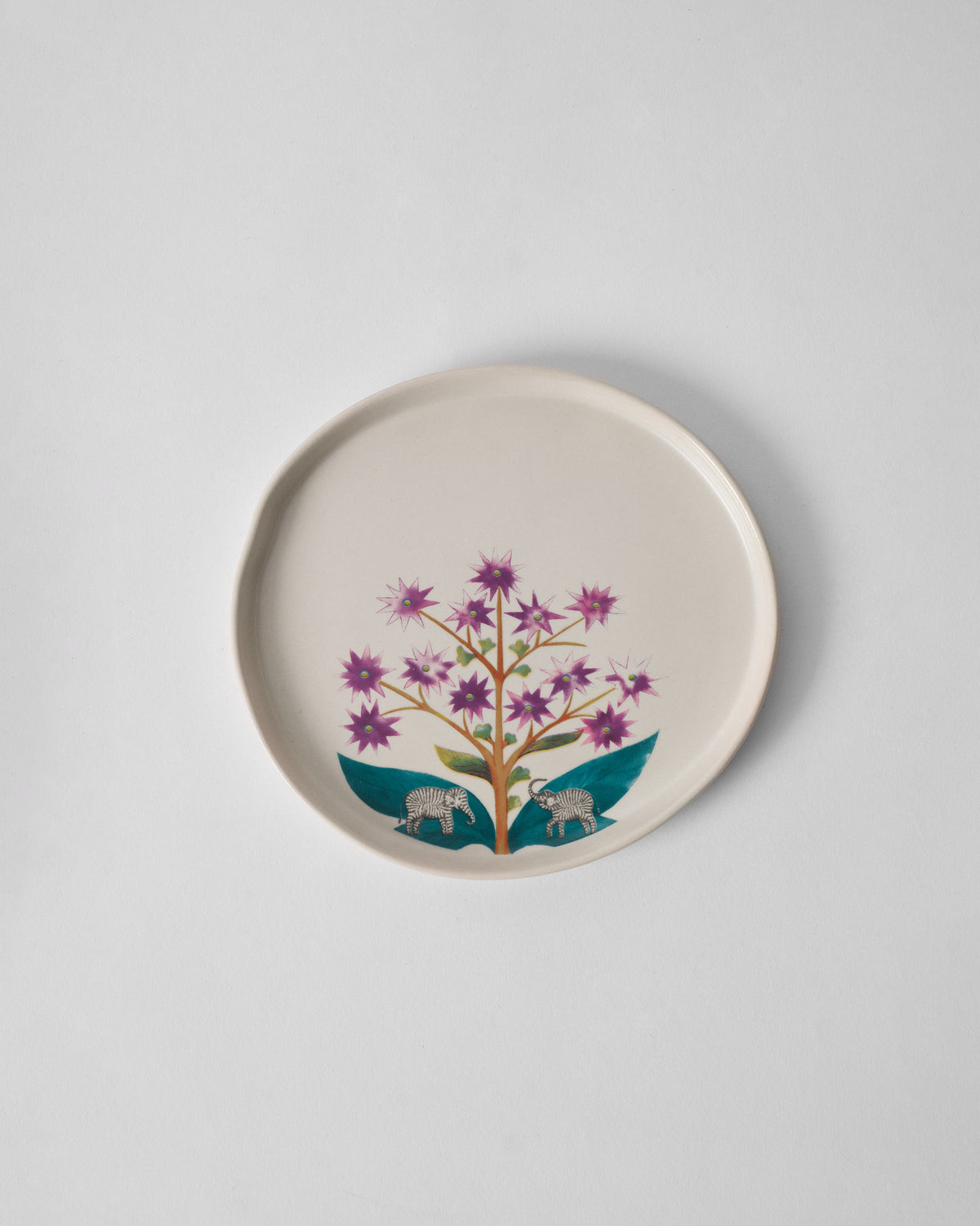 Overhead view of the Mogra Dessert Plate with purple flowers and teal leaves.