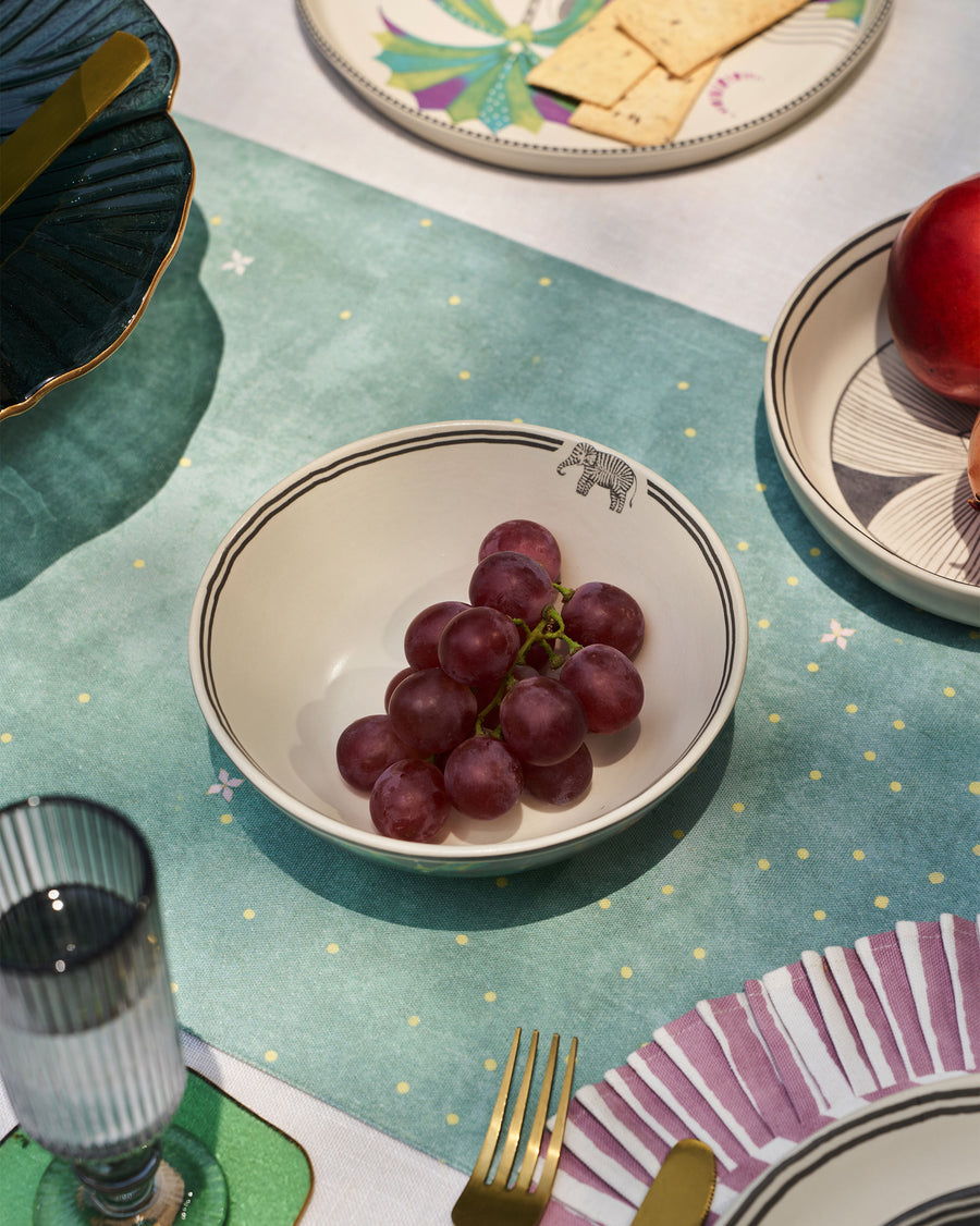 The Palm Bloom bowl holding grapes on a teal starry cloth