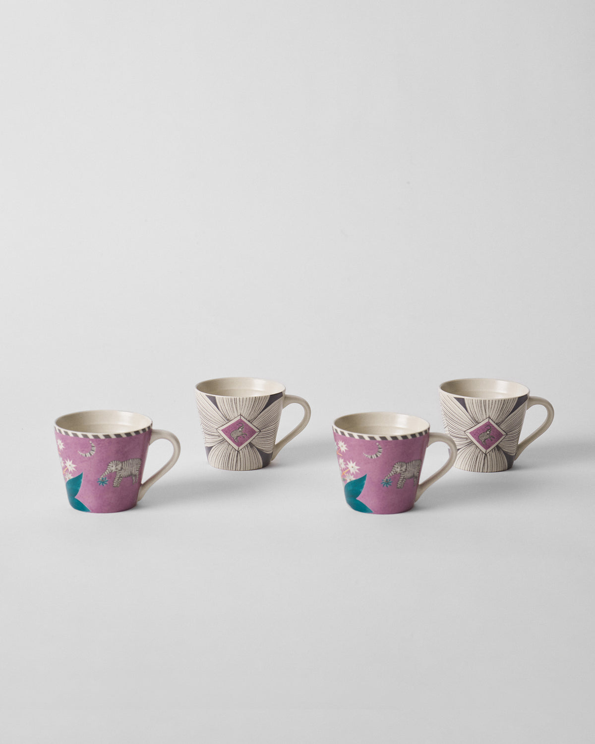 Four Mogra Bloom espresso mugs lined up, alternating magenta elephant and cream floral prints.