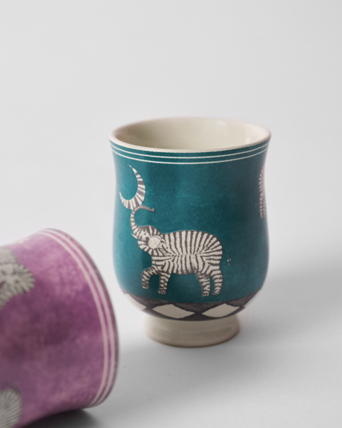 Close-up of a teal Tusk tea cup with a striped elephant and moon.