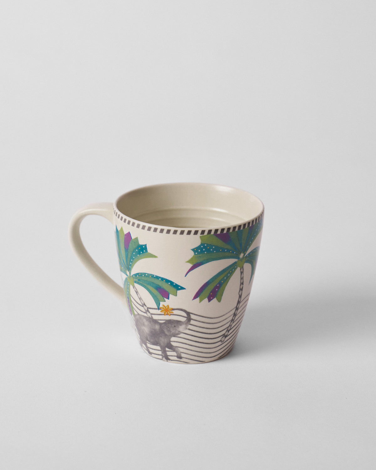 Tusk Conical Mug with a palm tree and grey elephant, handle on the left.