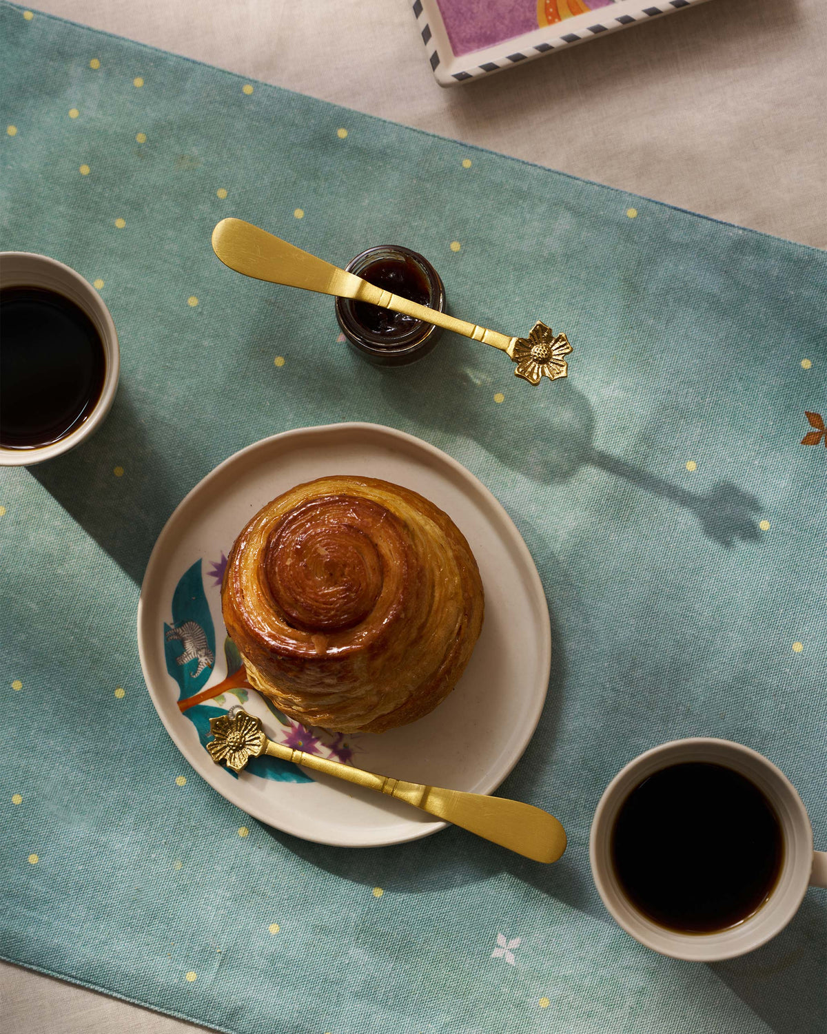 Phool butter knives with jam and pastry on a teal breakfast setting.
