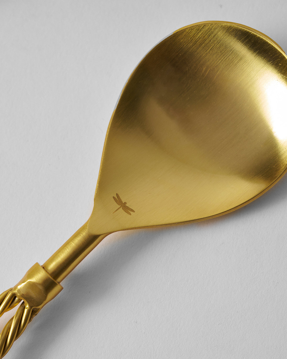 Close-up of a Tusk serving spoon with a dragonfly mark.