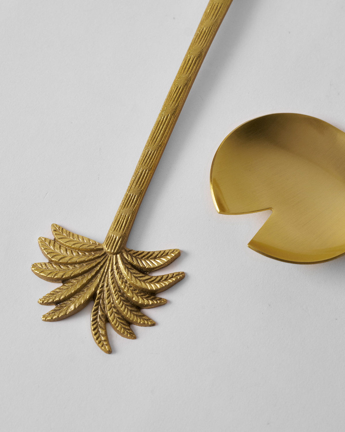 Close-up of a Palm Bloom salad server palm finial and notched spoon head.