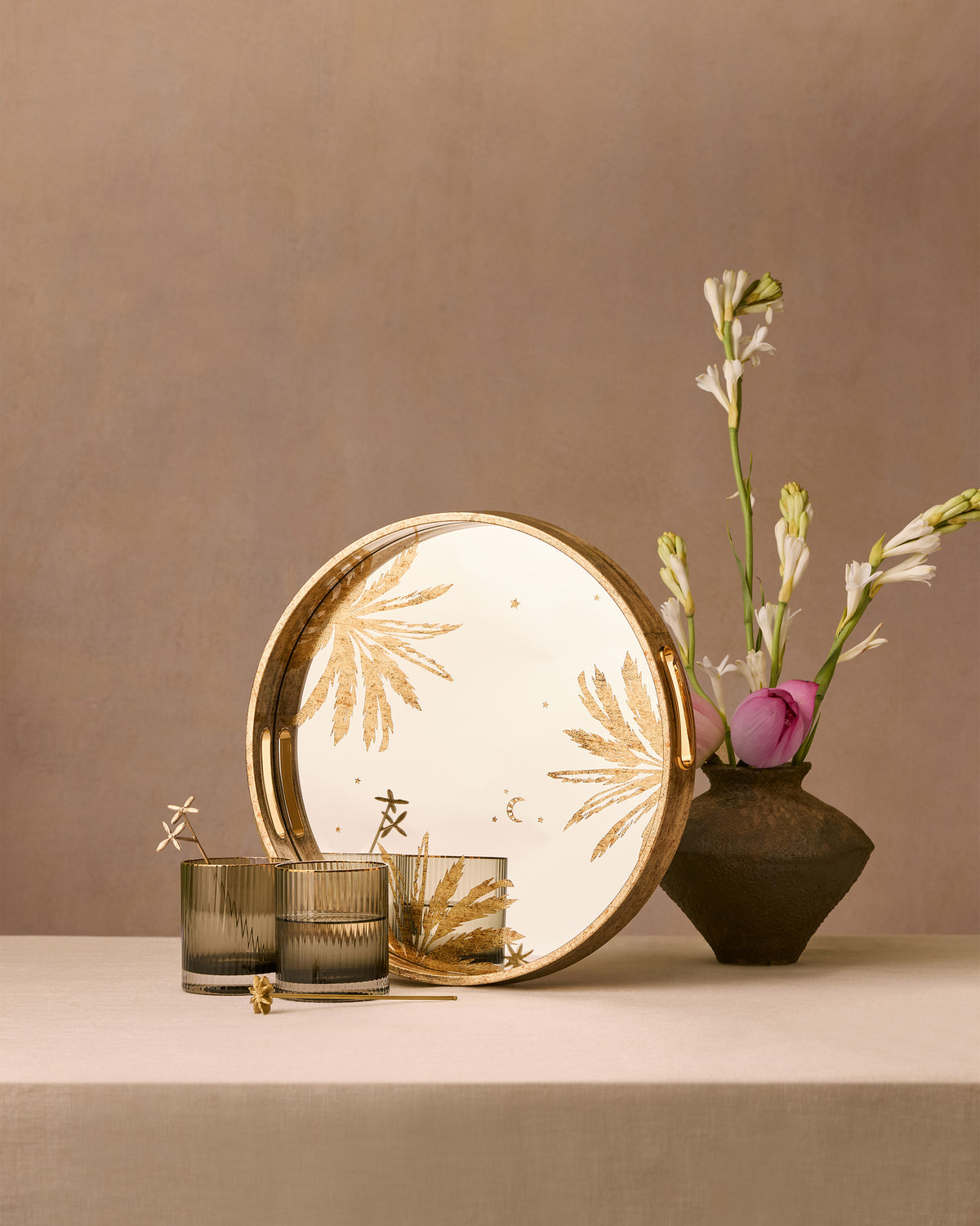 Gilded Palm tray and fluted glasses styled on a table with a flower vase.