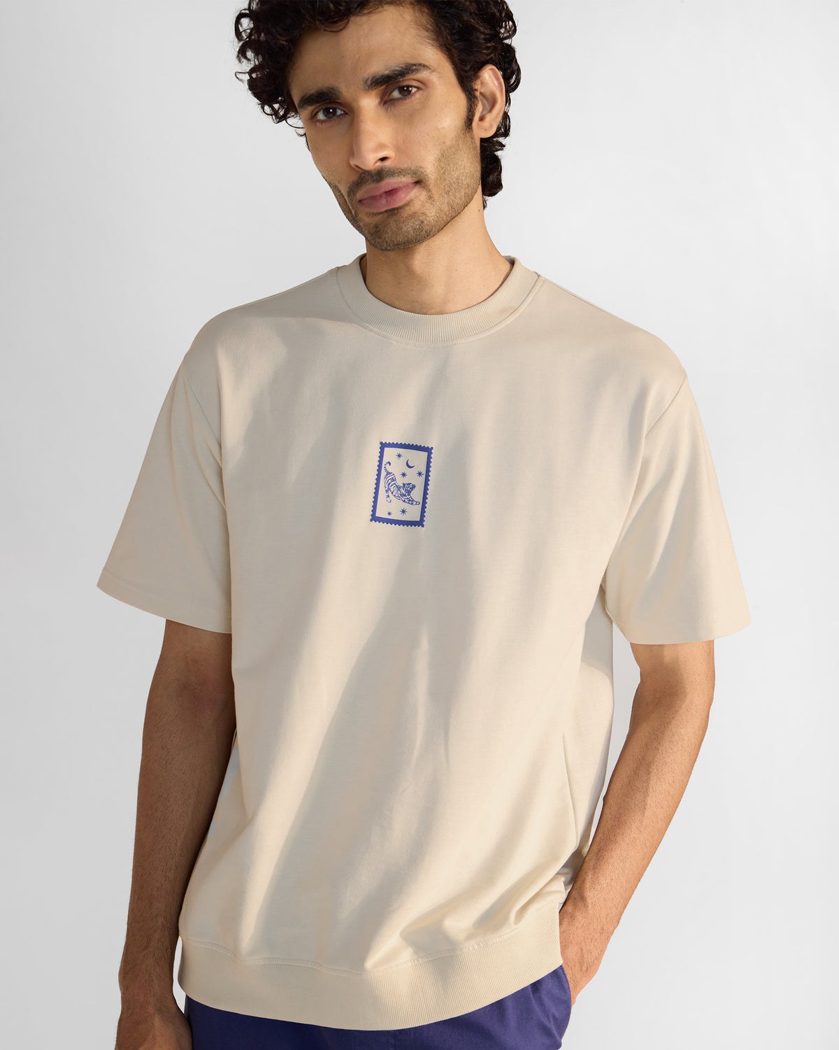 Person wearing an ivory short-sleeve leaping tiger t-shirt with a chest stamp.