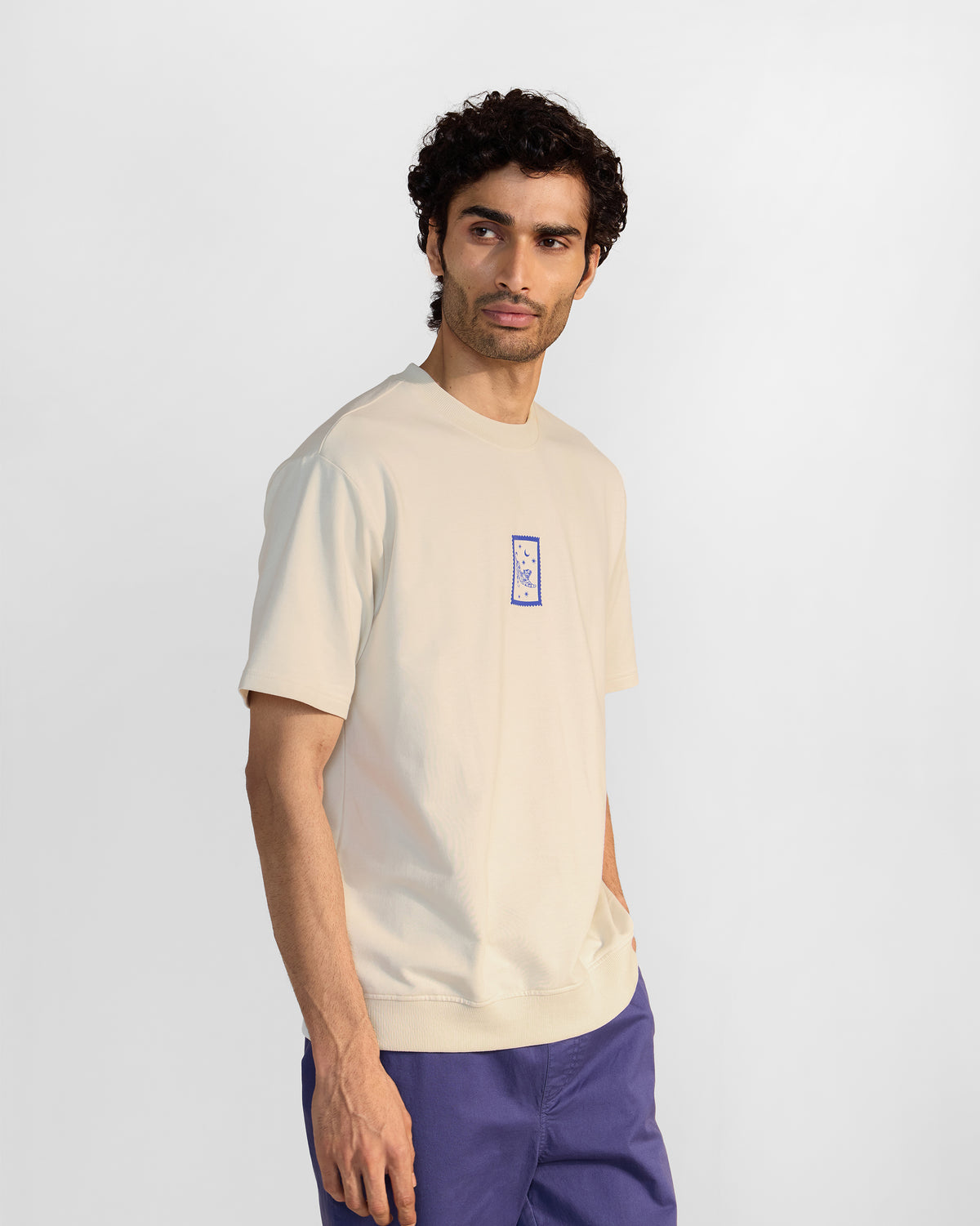 Three-quarter view of an ivory leaping tiger t-shirt with a blue chest stamp.
