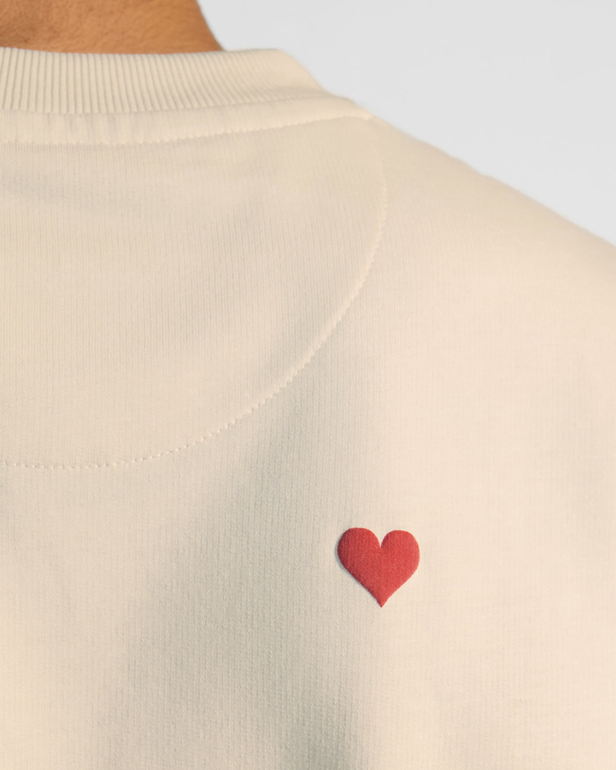 Close-up of a small red heart on the upper back of an ivory leaping tiger tee.
