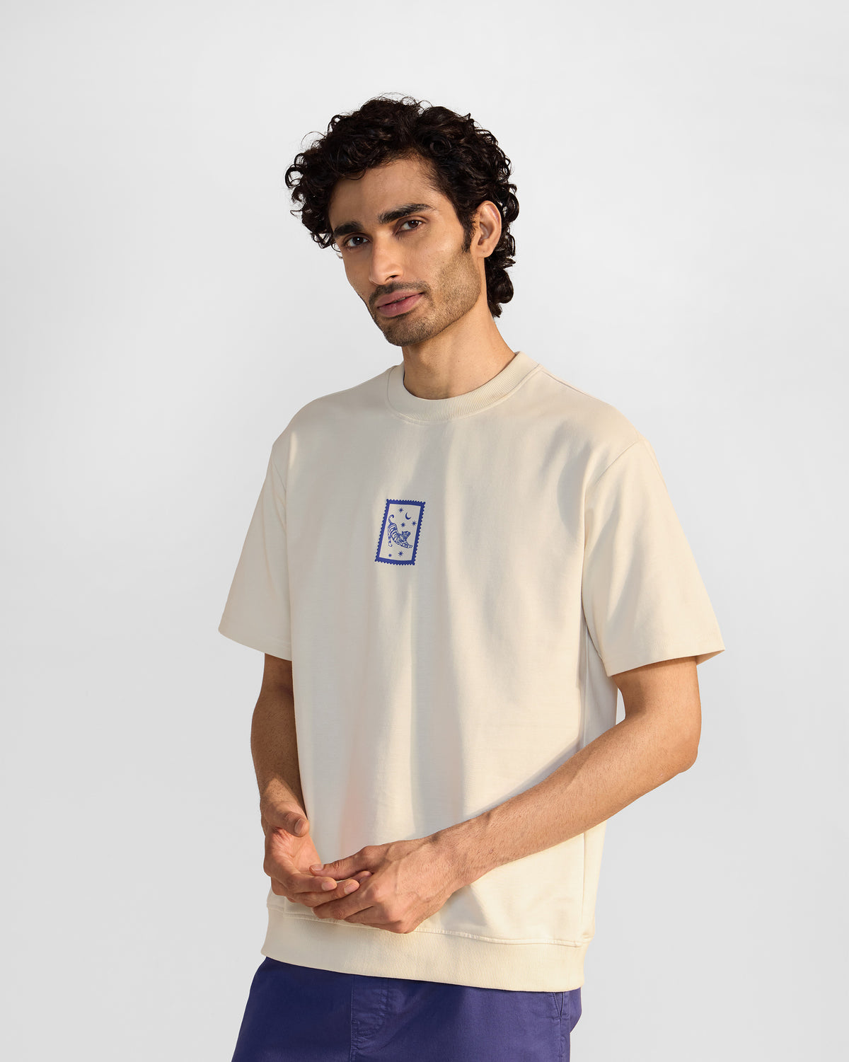 Ivory leaping tiger t-shirt with a small blue tiger stamp print on the chest.