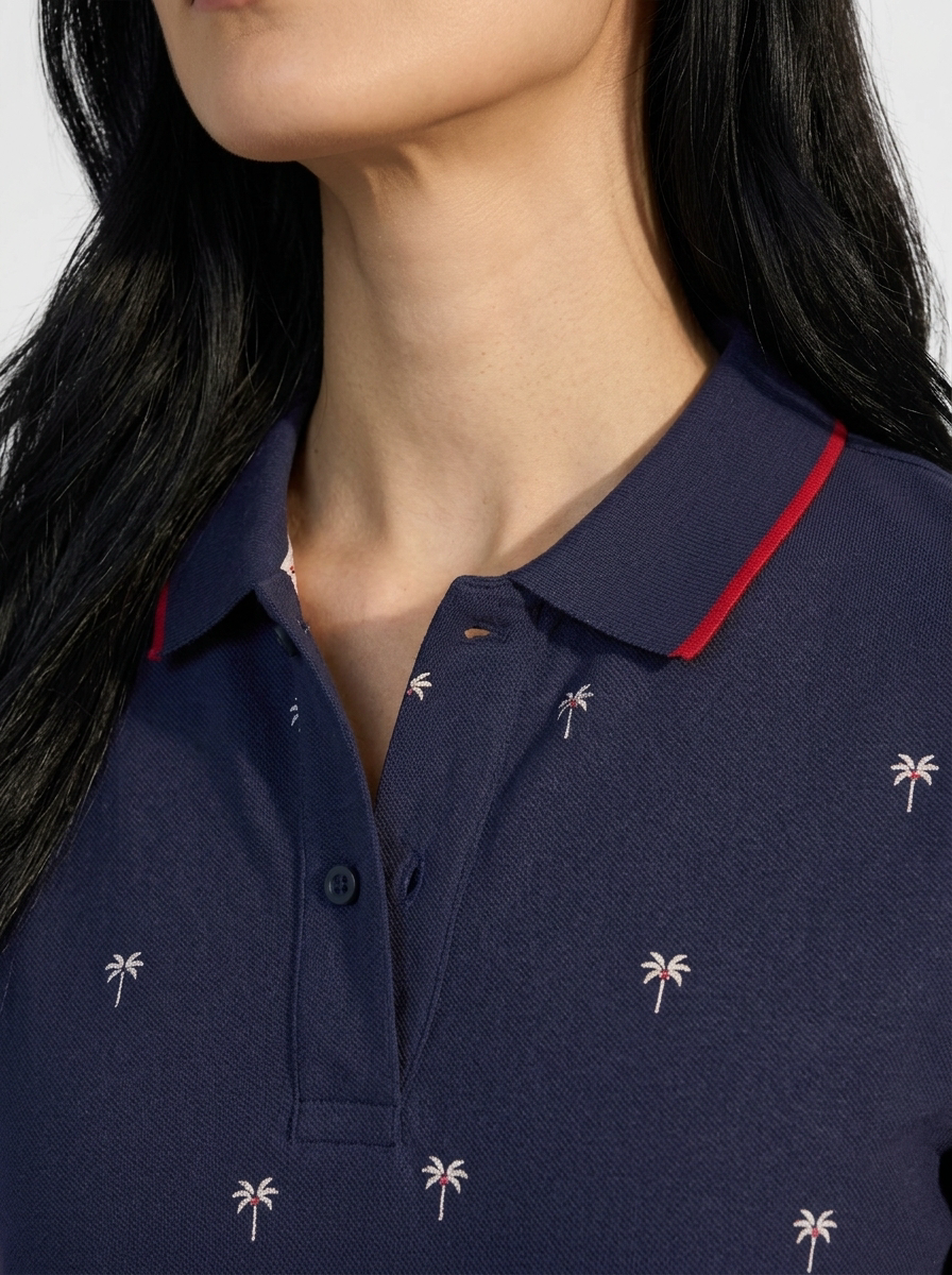 Close-up of the collar and placket of an ink blue Palma polo with red tipping.