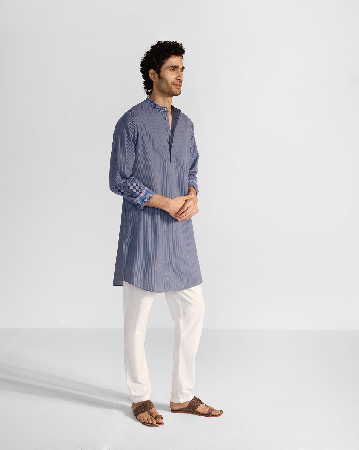 Person wearing a navy and white striped Nysa Kurta with rolled check-lined cuffs.
