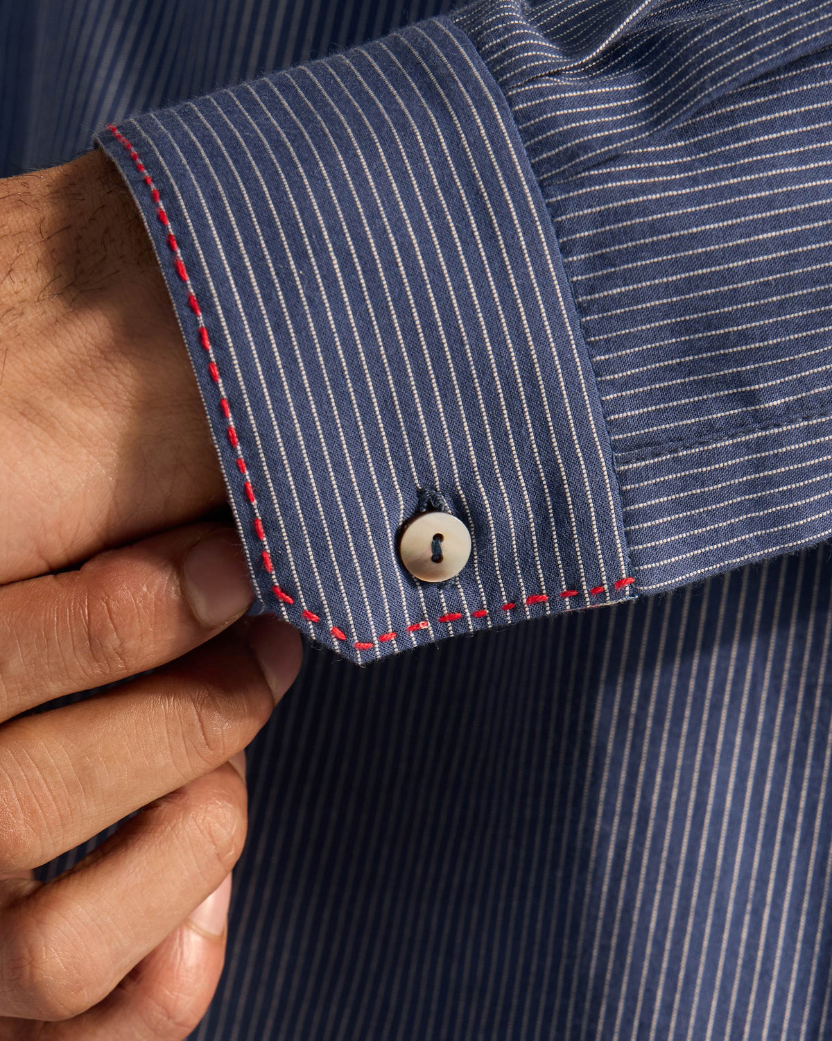 Close-up of a navy striped Nysa Kurta cuff with red contrast stitching.