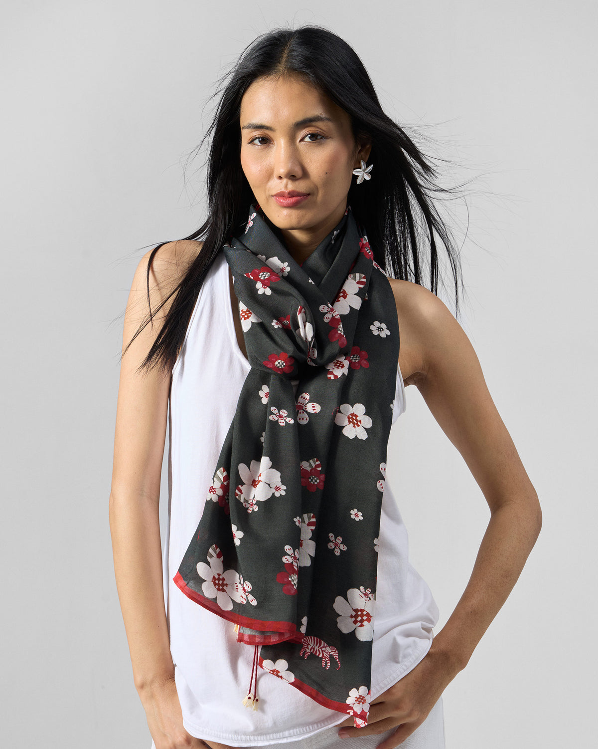 Person wearing the Fleur Scarf in red and black draped at the neck.