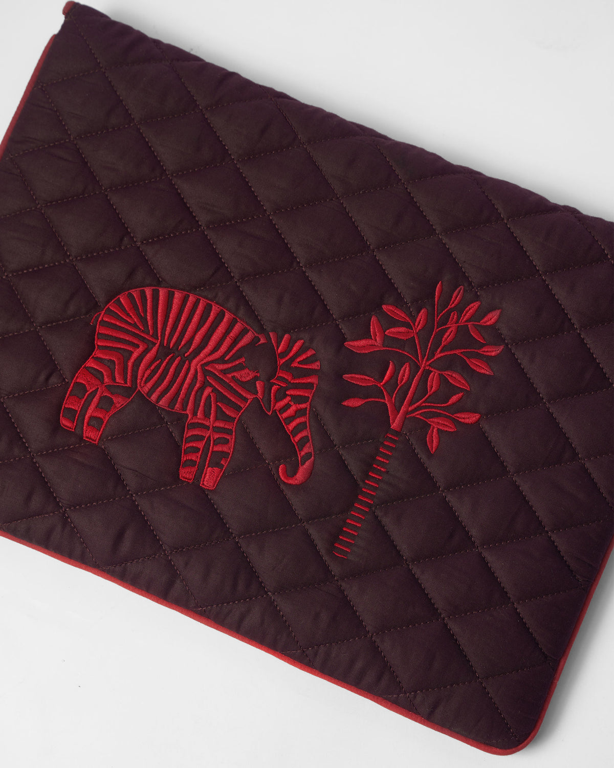 Close-up of red elephant embroidery on a brown Ele laptop sleeve.