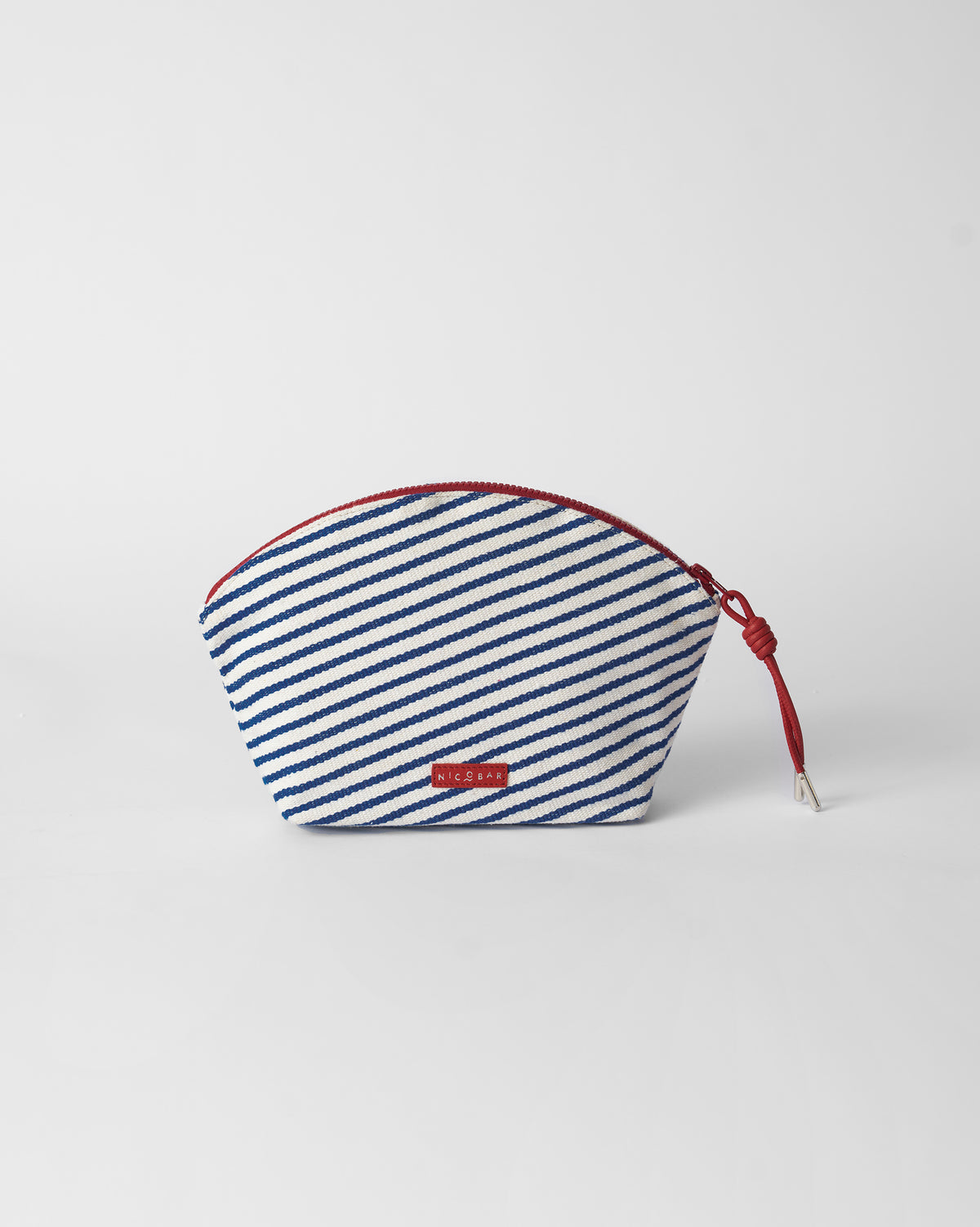 Back of the blue and white Kira Pouch with a red zipper and Nicobar label.