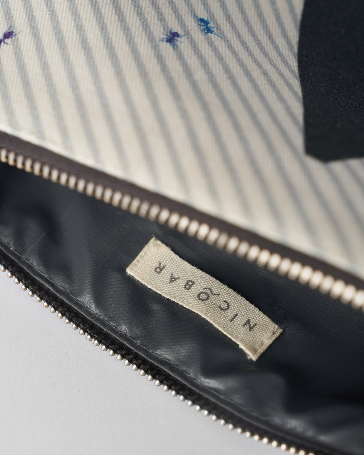 Open ivory Anaar Pouch showing the Nicobar label and striped lining.