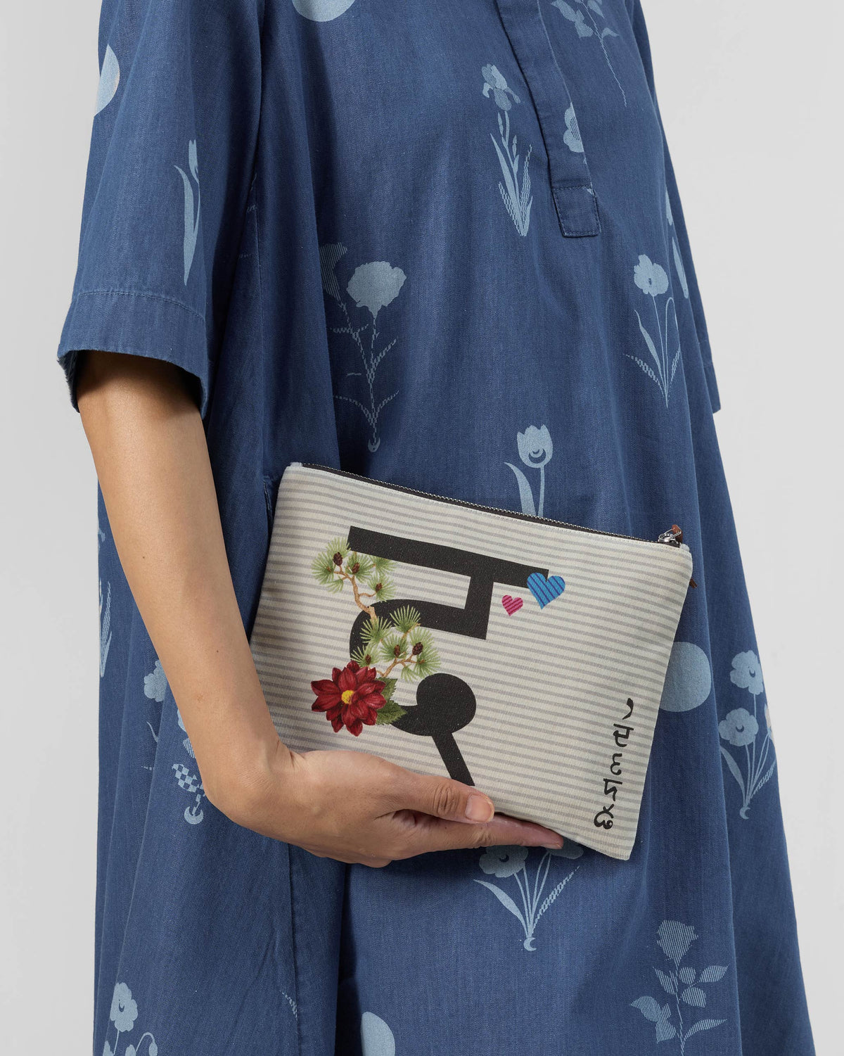 Ivory Dil Pouch with a black letter print, red flower, and small hearts.