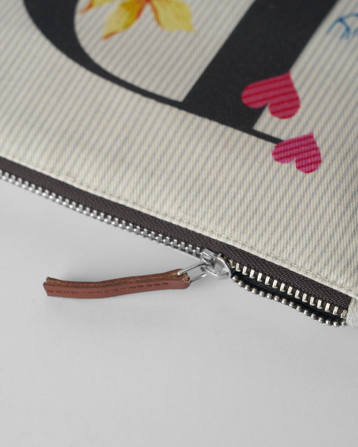 Close-up of the brown leather zipper pull on an ivory Dil Pouch.