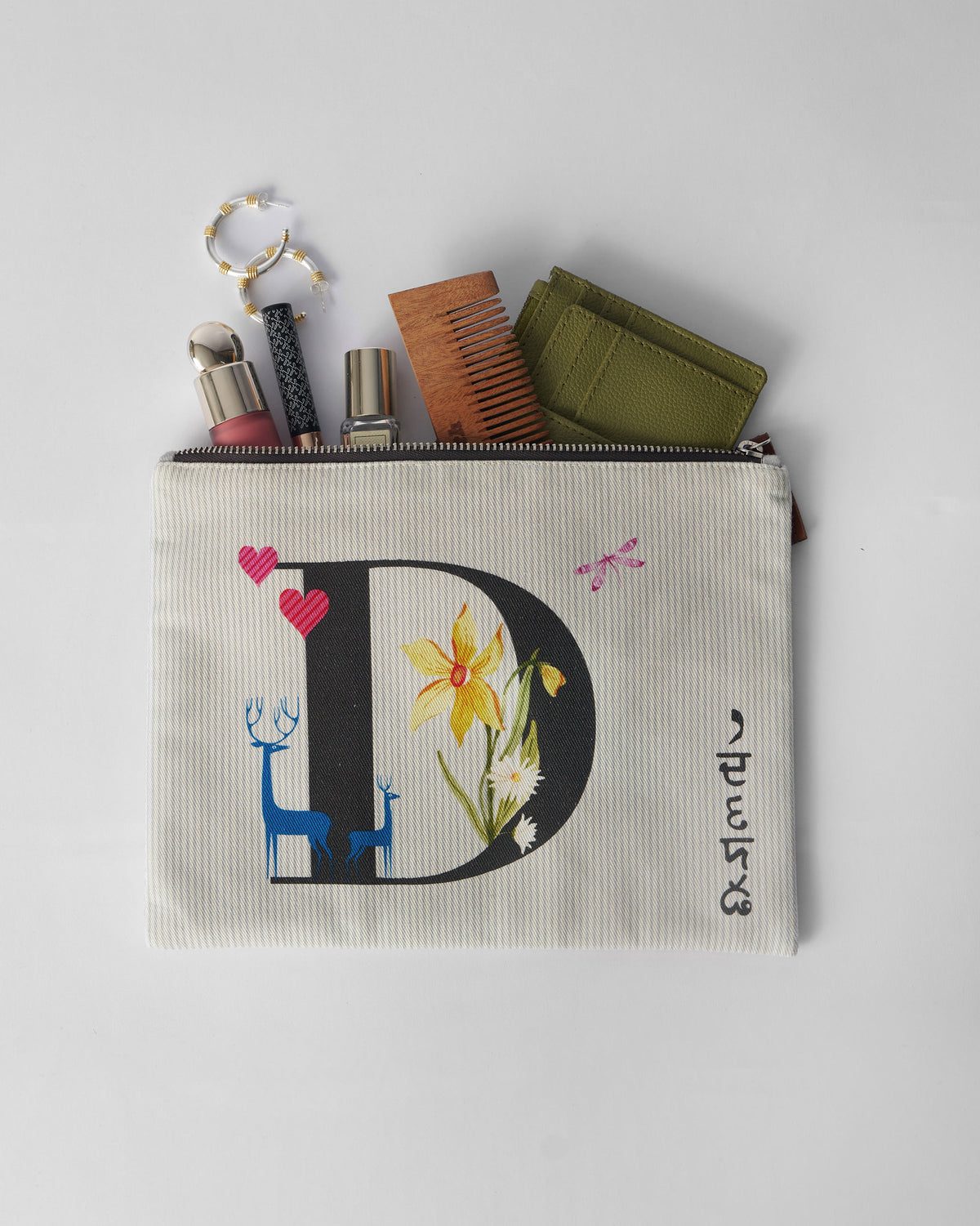 Open ivory Dil Pouch packed with a comb, bottle, and small essentials.