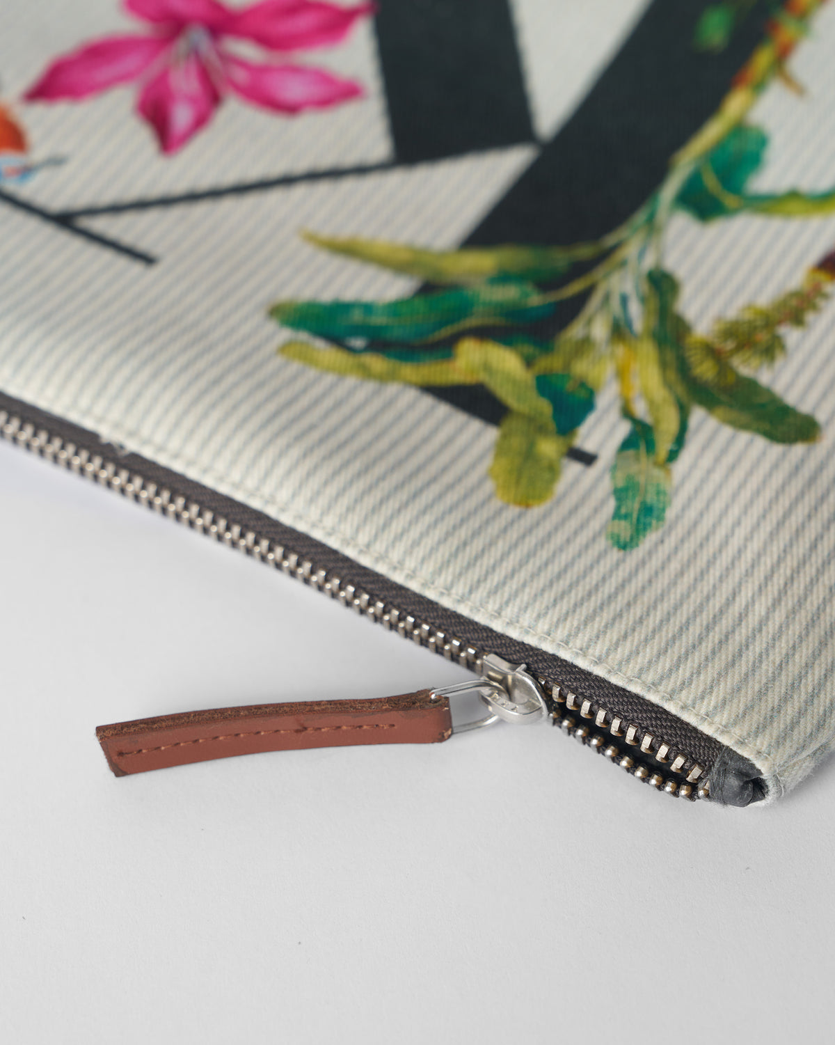 Close-up of the brown leather zipper pull on an ivory Kamal Pouch.