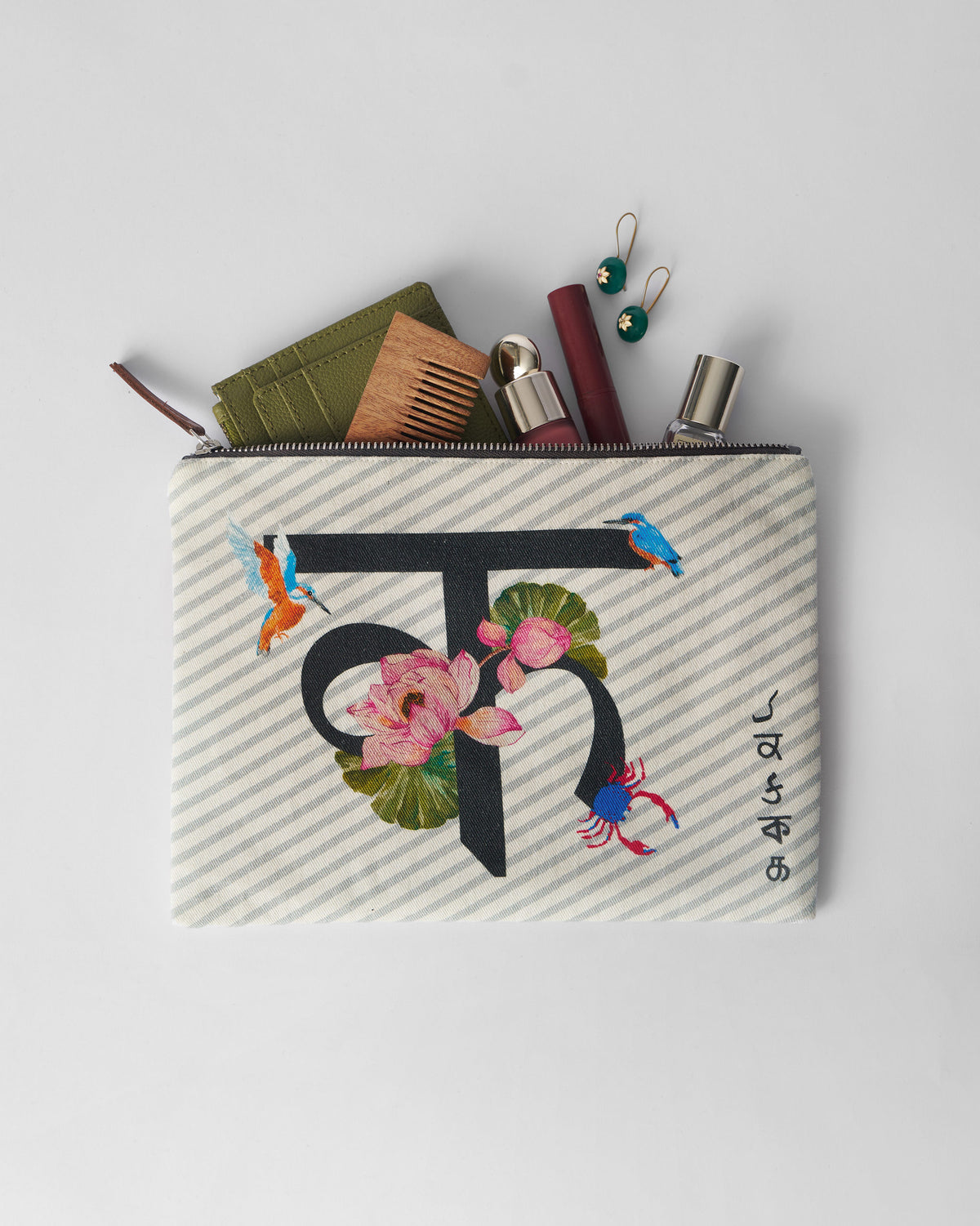 Open ivory Kamal Pouch packed with a comb, wallet, and small essentials.