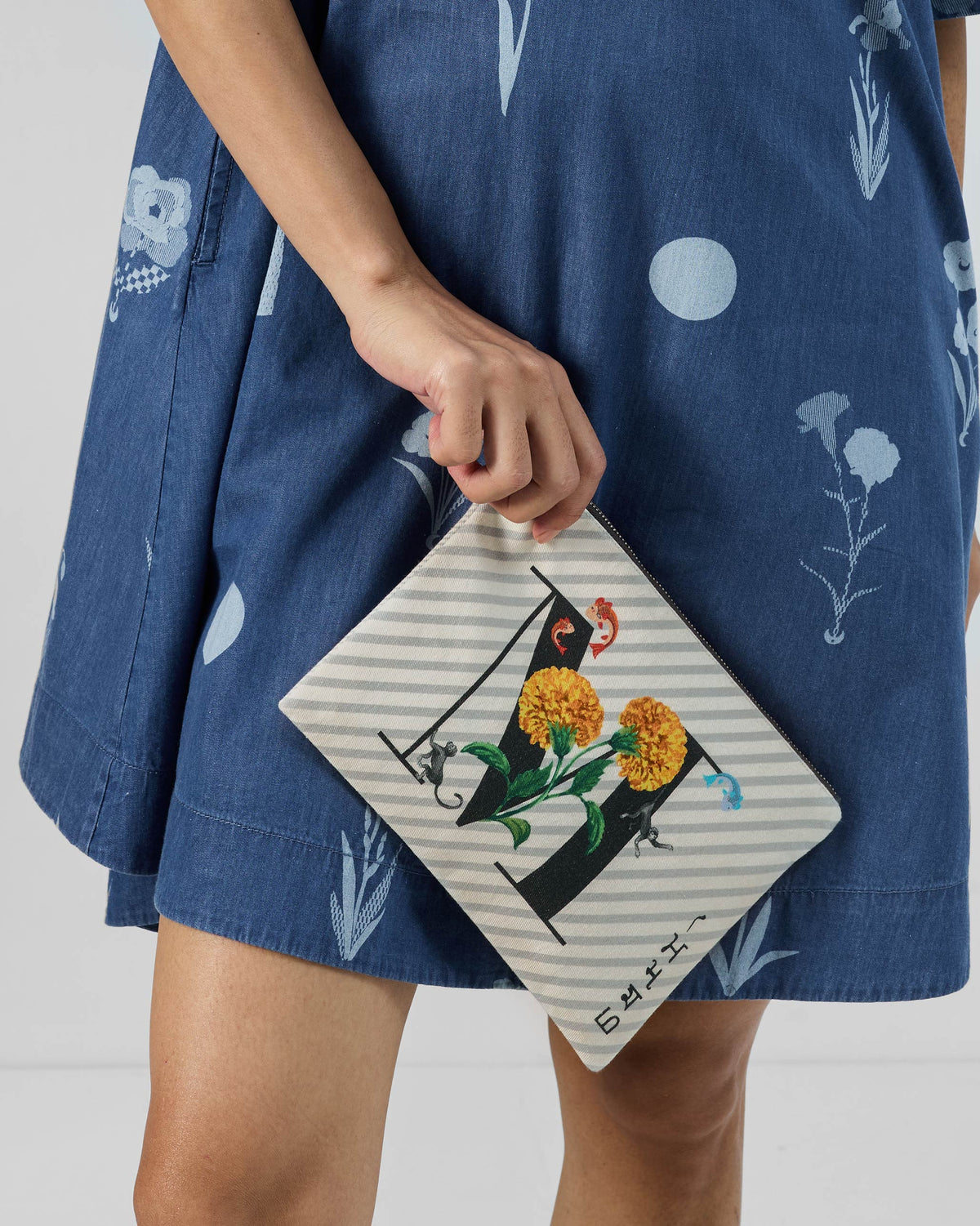Ivory Machli Pouch with a black M print, marigolds, fish, and monkeys.