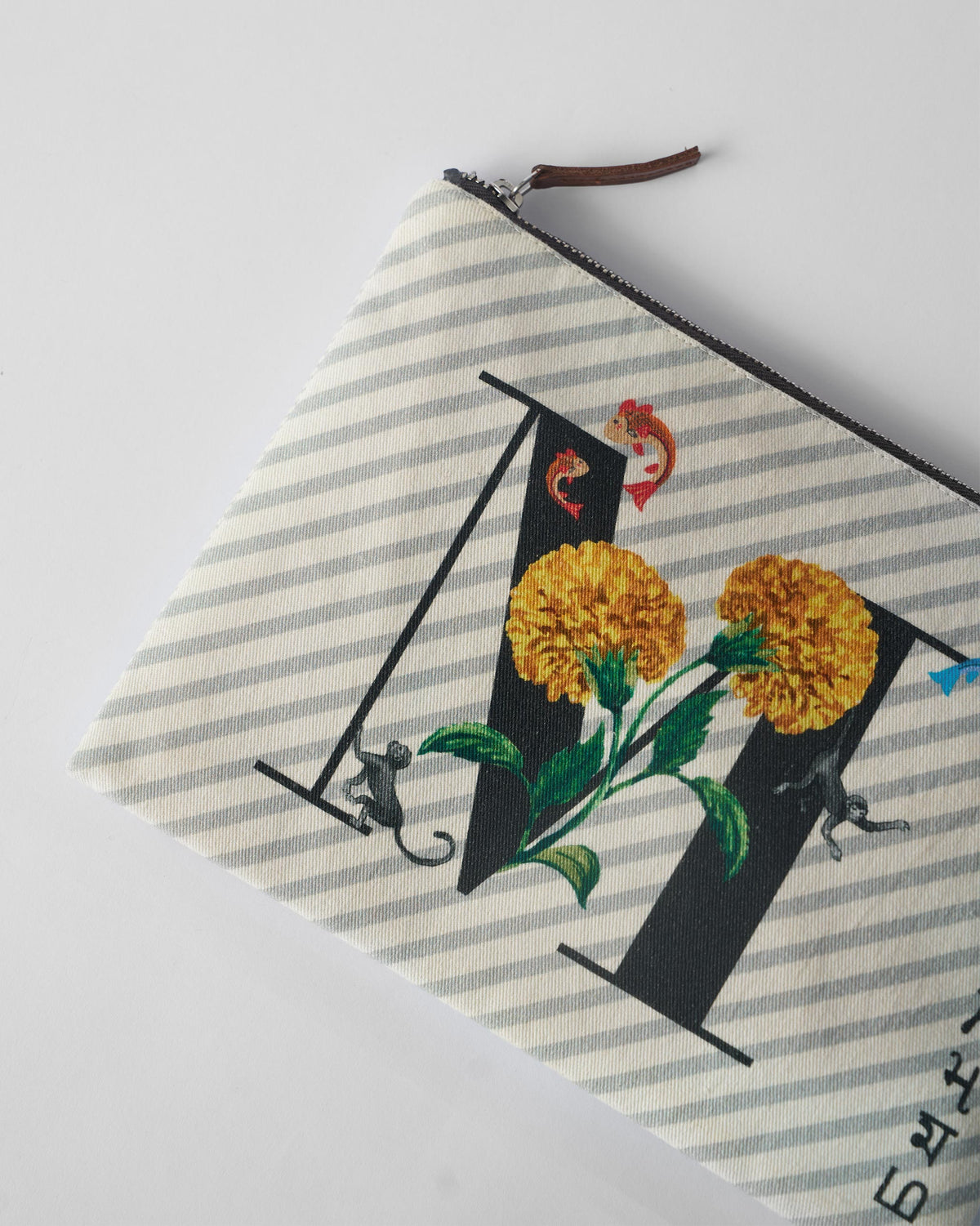 Close-up of marigold, fish, and monkey print on an ivory Machli Pouch.