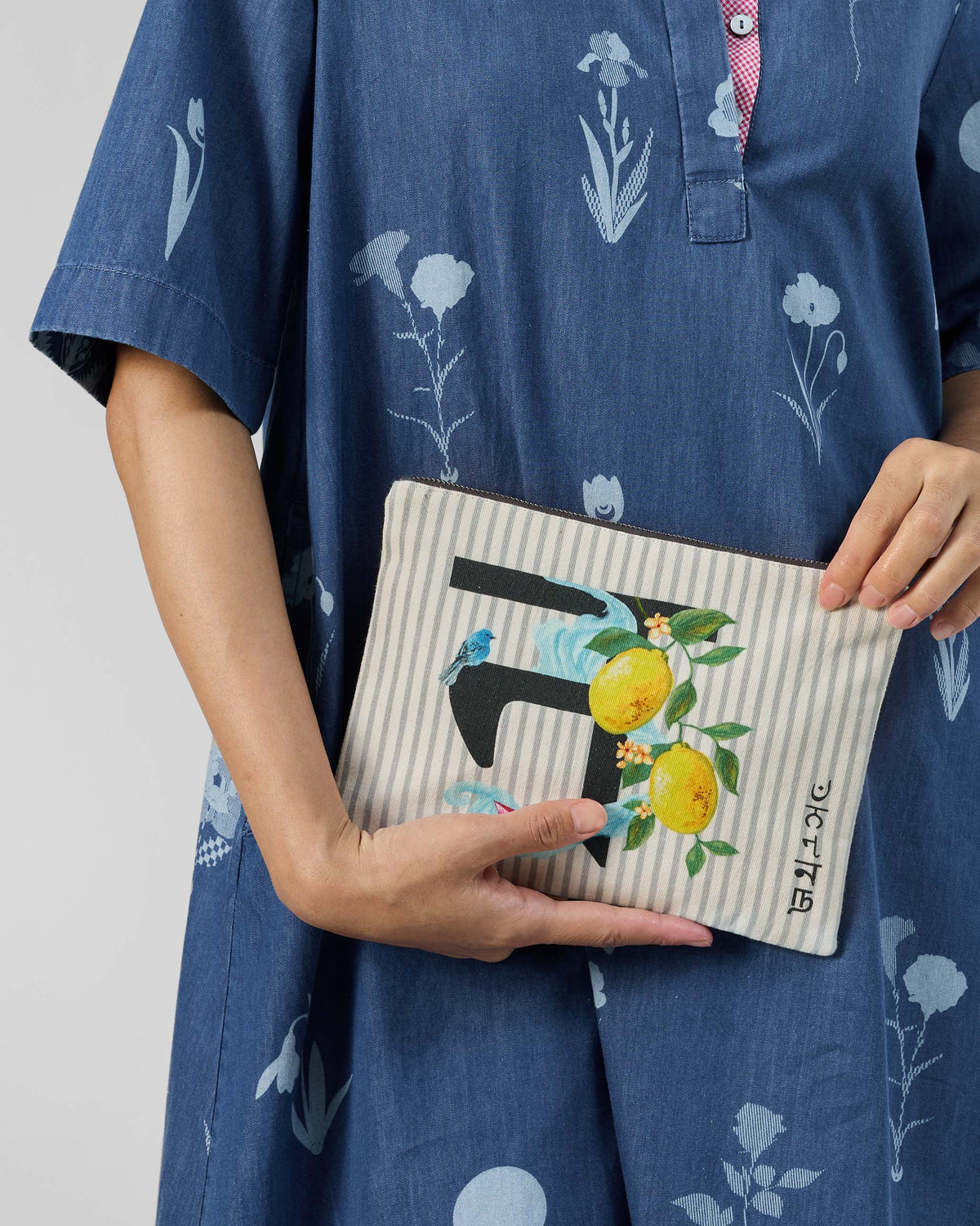 Ivory Nilambari Pouch with a black letter print, yellow lemons, and a blue bird.