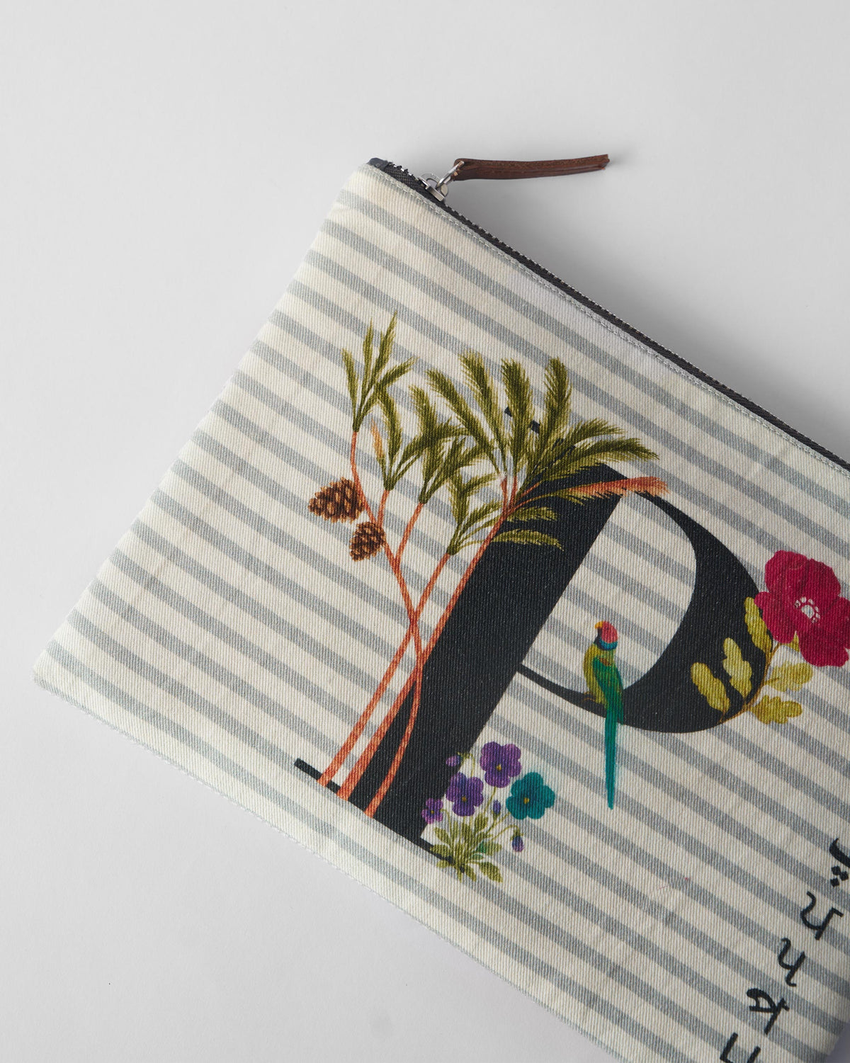 Close-up of palm, flower, and bird print on an ivory Palash Pouch.