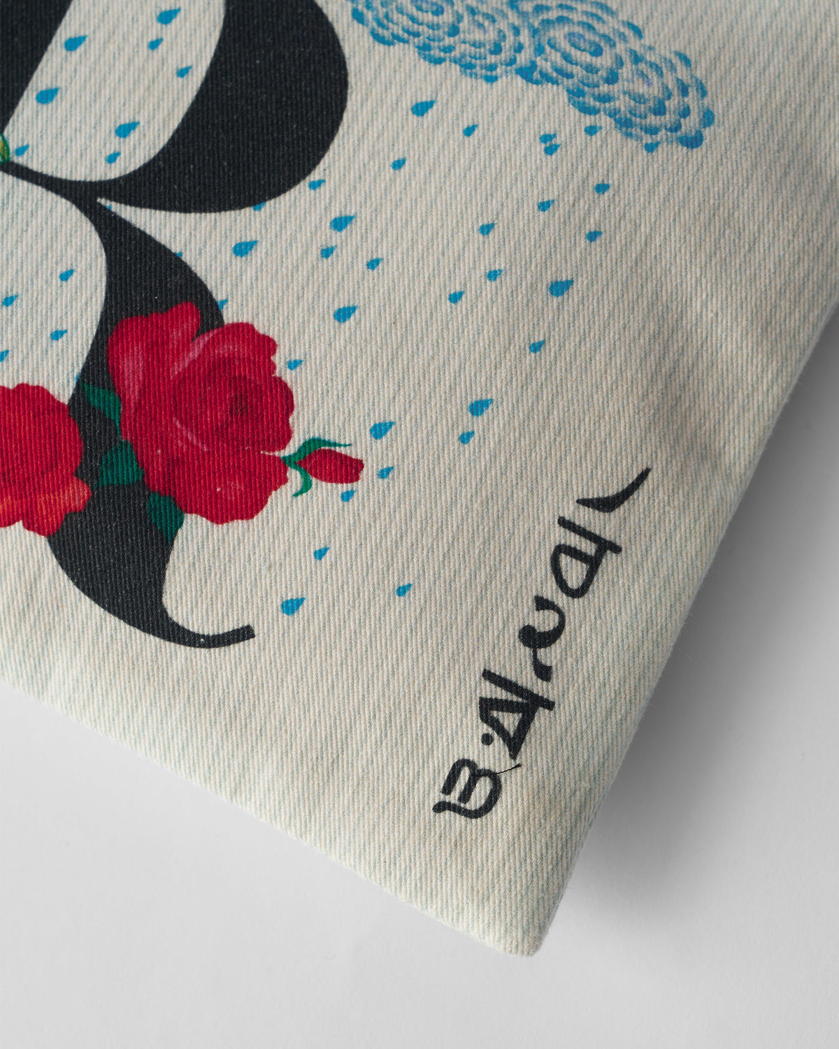 Close-up of red roses and a rain cloud print on an ivory Rimjhim Pouch.