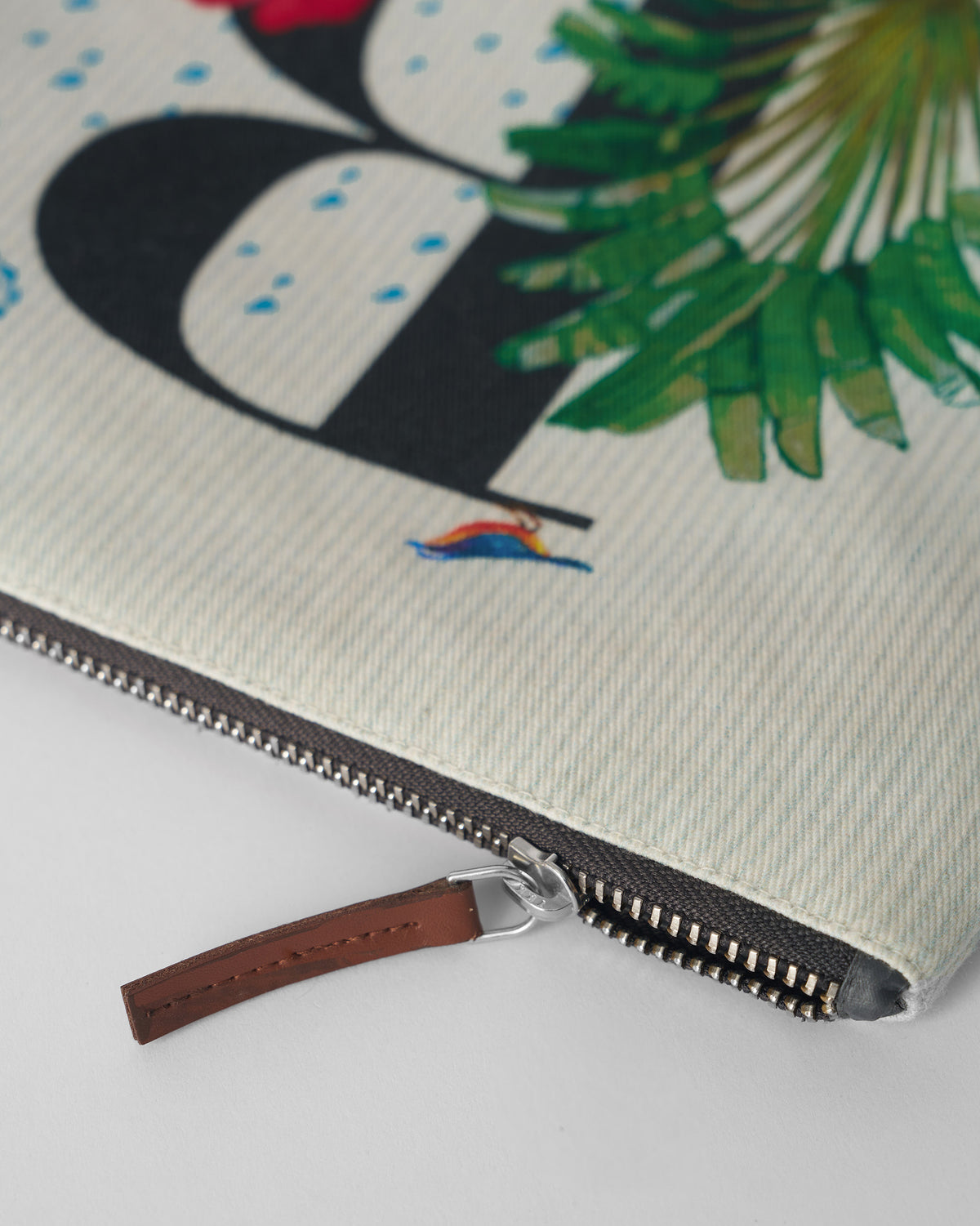 Close-up of the brown leather zipper pull on an ivory Rimjhim Pouch.