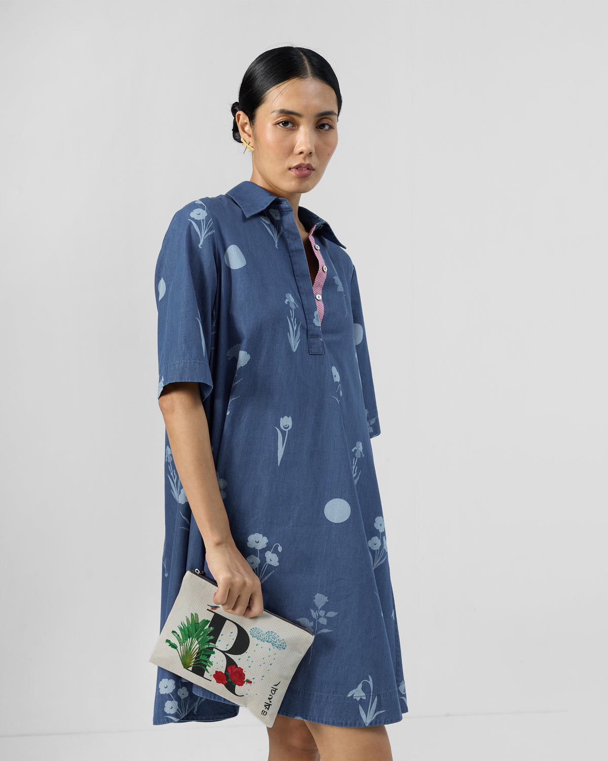 Ivory Rimjhim Pouch with a black R print and rain motif, held at the hip.