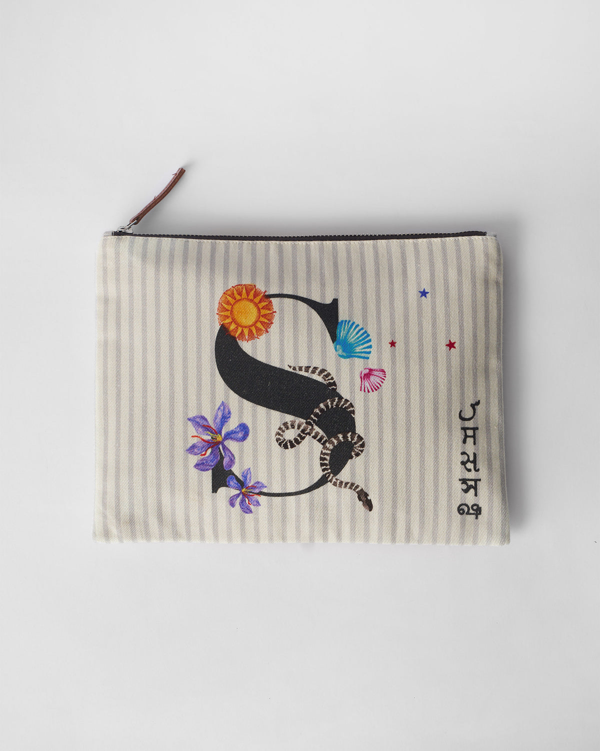 Ivory Sitara Pouch with a black letter S decorated with sun, snake, and flowers.